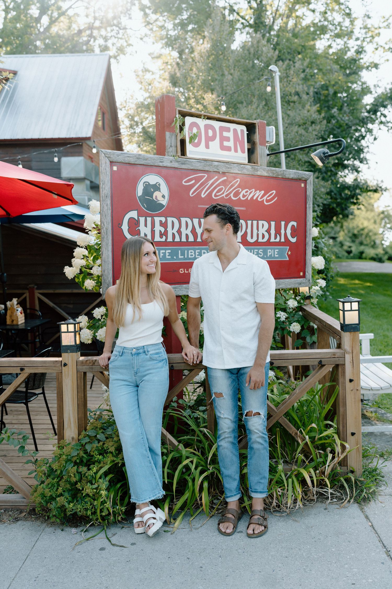 A couple stands together outside the Cherry Public restaurant with an open sign visible.