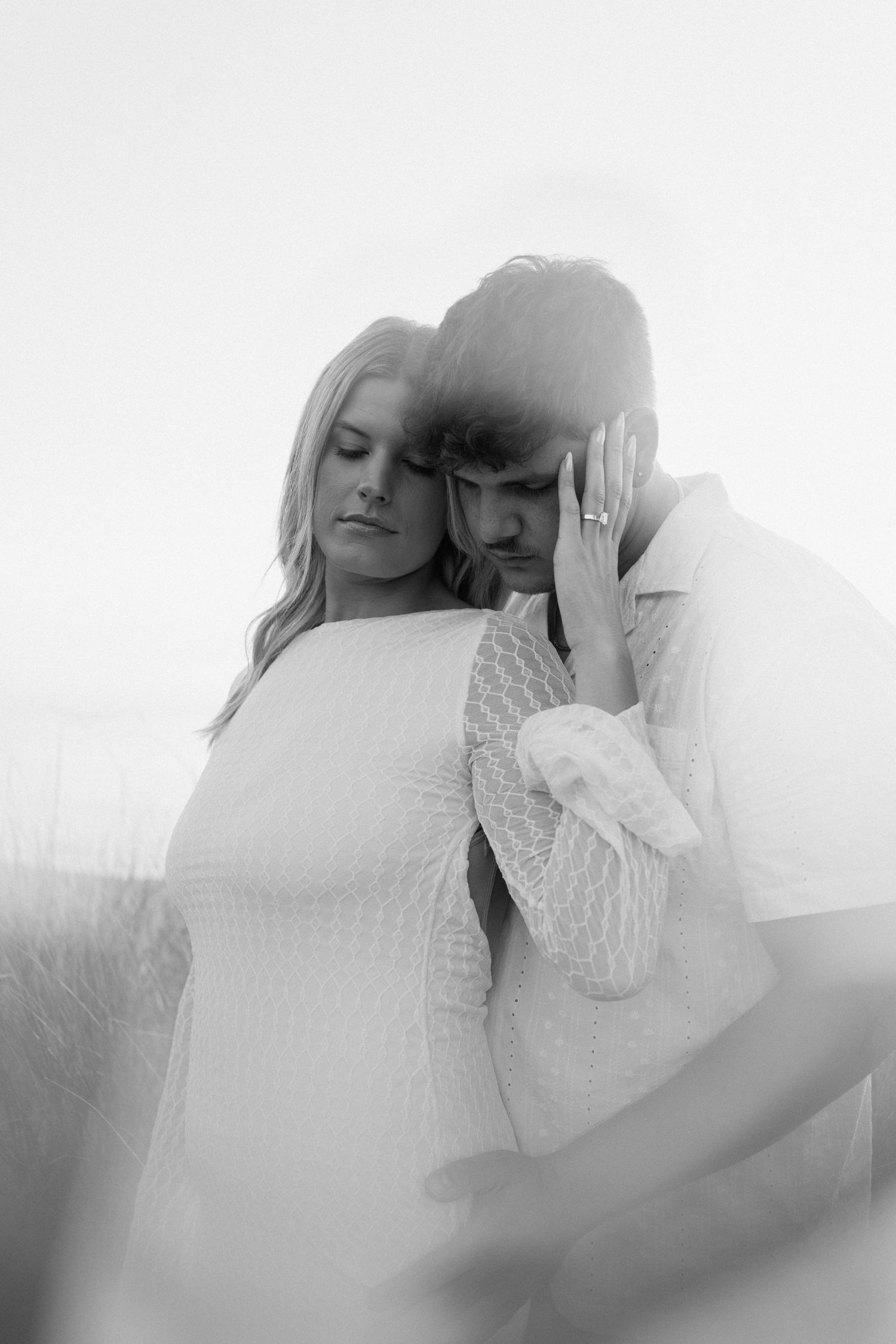 An intimate black and white portrait of a couple embracing in soft focus.