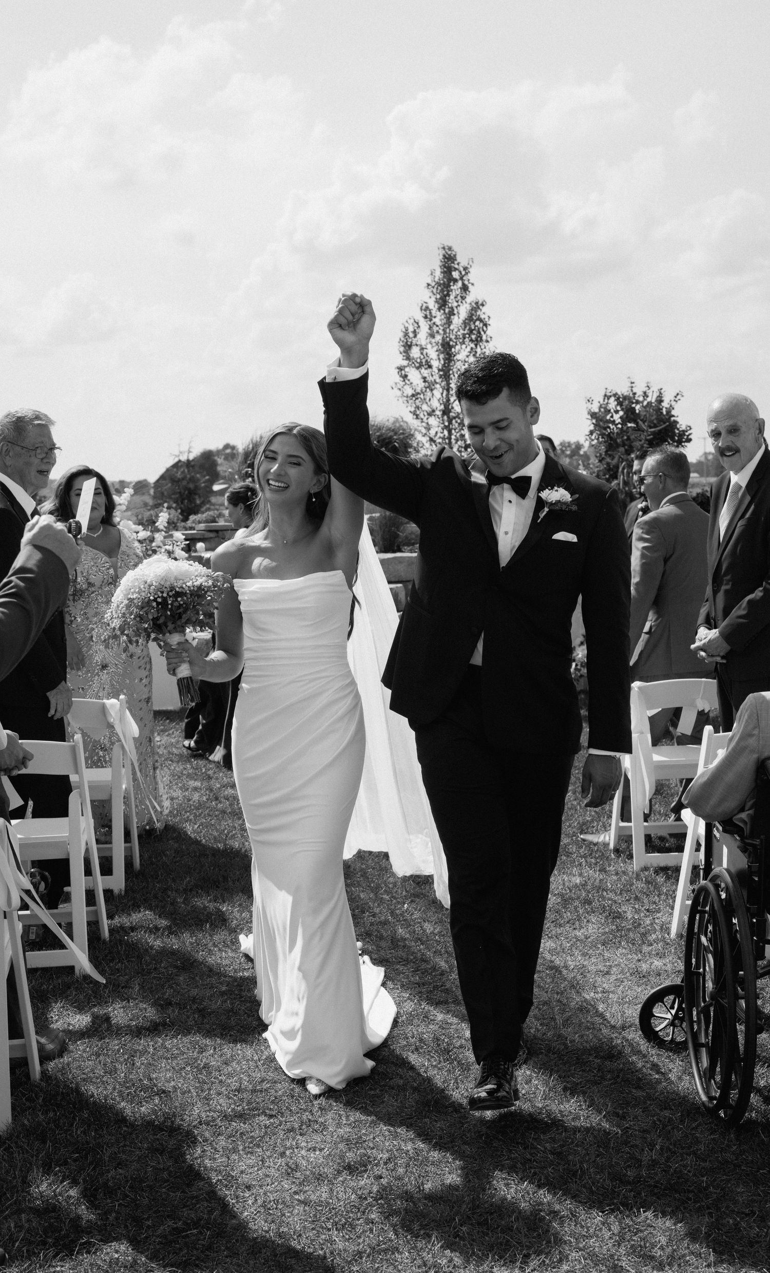 Black and white wedding ceremony photo showing joyful celebration in outdoor garden setting.