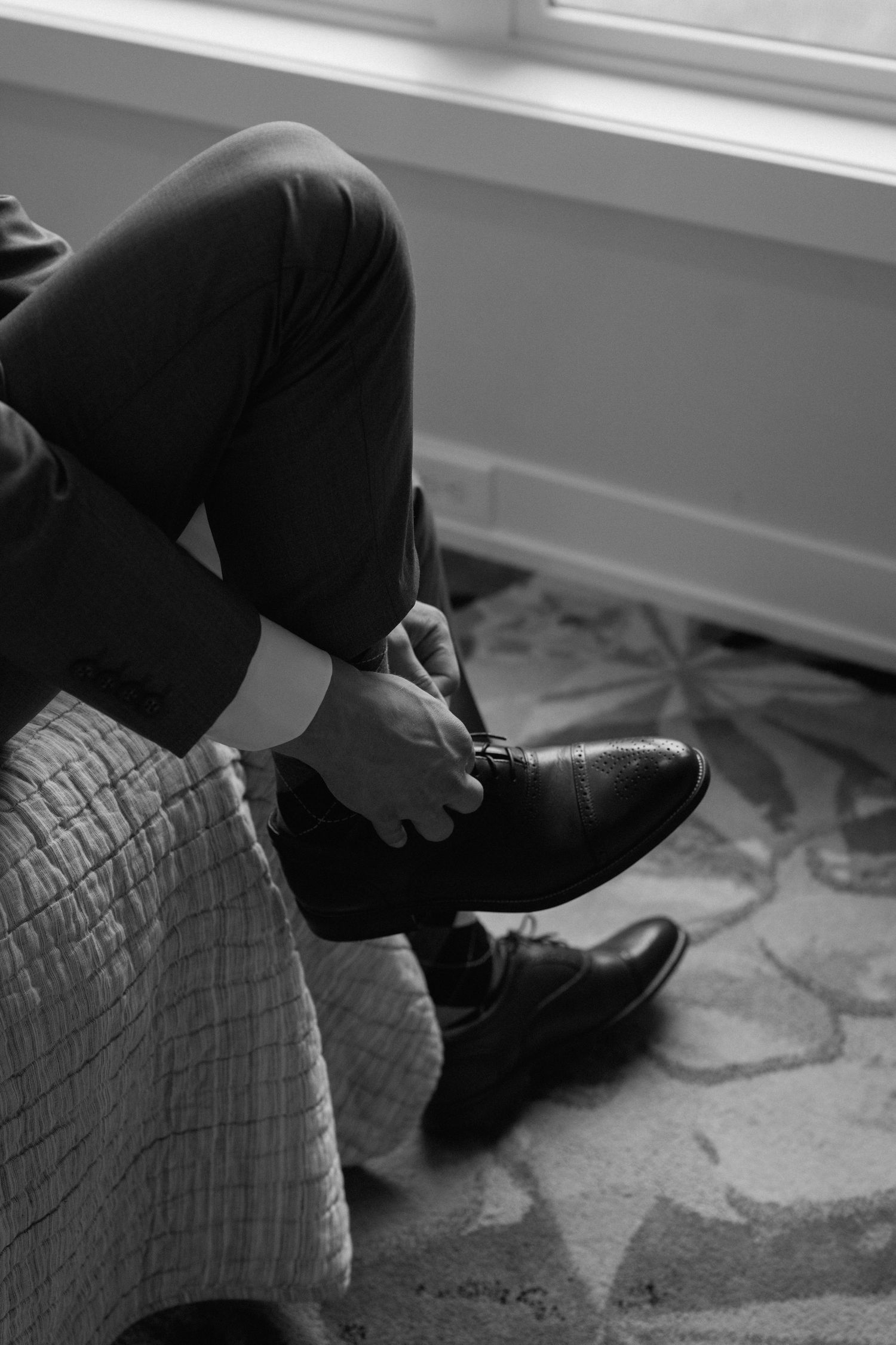 Black and white photo of formal dress shoes being put on before a wedding ceremony.