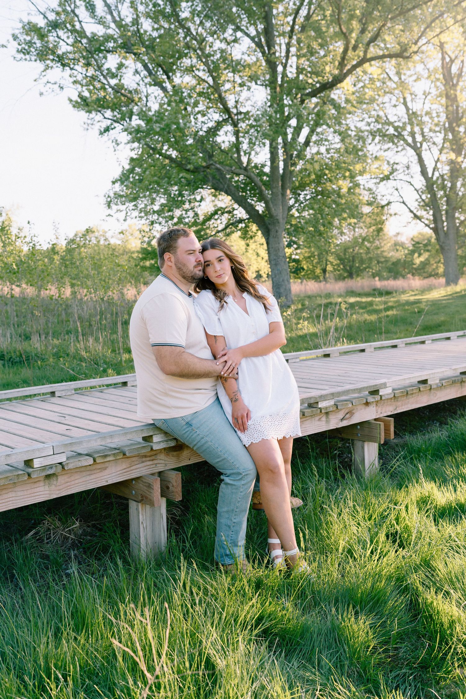 Romantic outdoor photo session on a wooden deck at sunset with golden light filtering through trees.