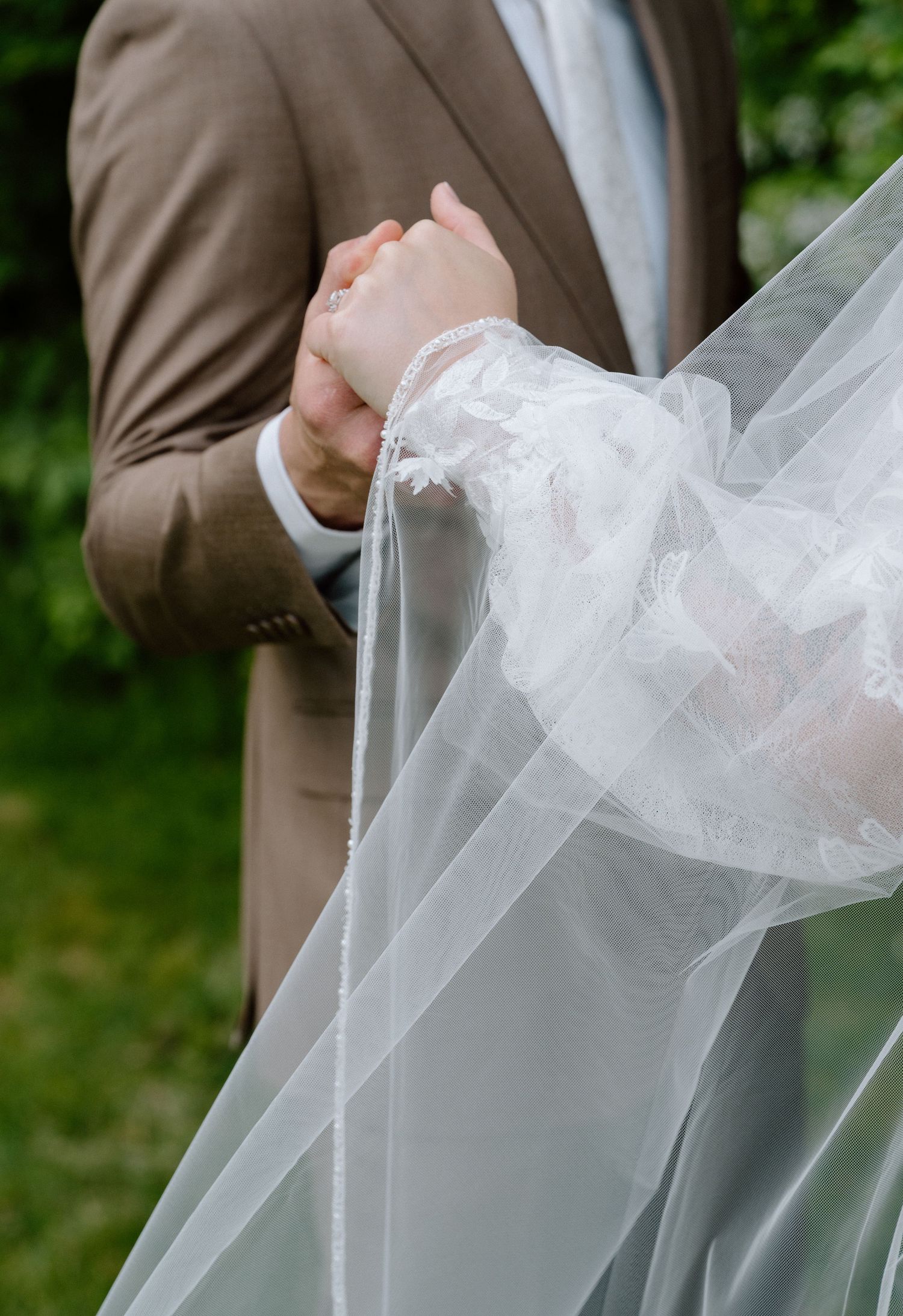 Close-up detail shot of hands adjusting white tulle wedding veil fabric.