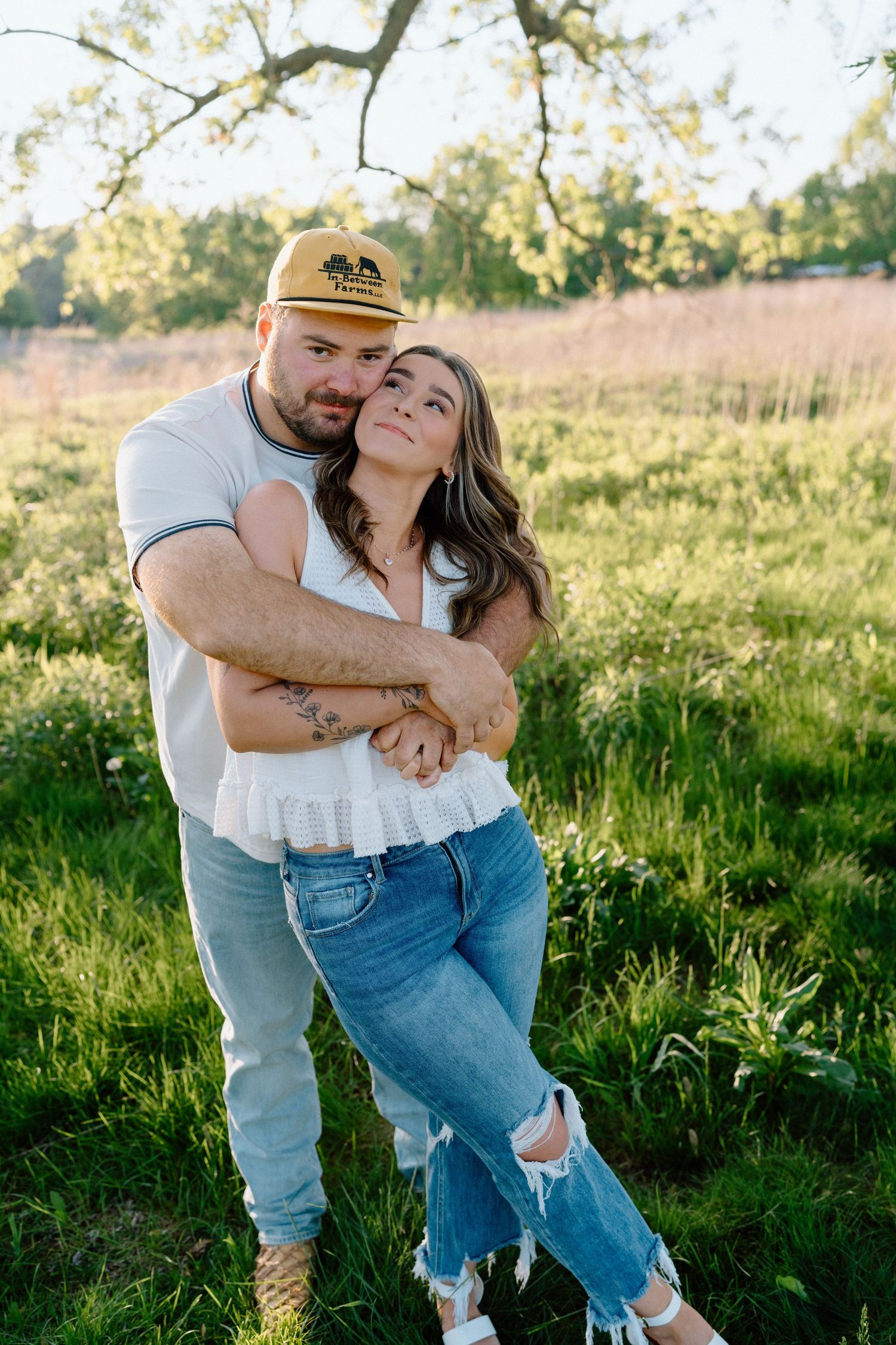 Couple in denim and white share a lighthearted moment in a sunny meadow.