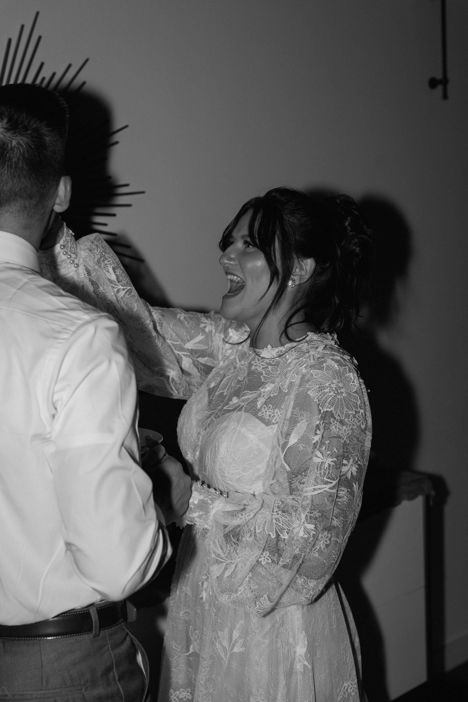 Artistic black and white wedding photo captures expressive dance movements in a shadowy setting.