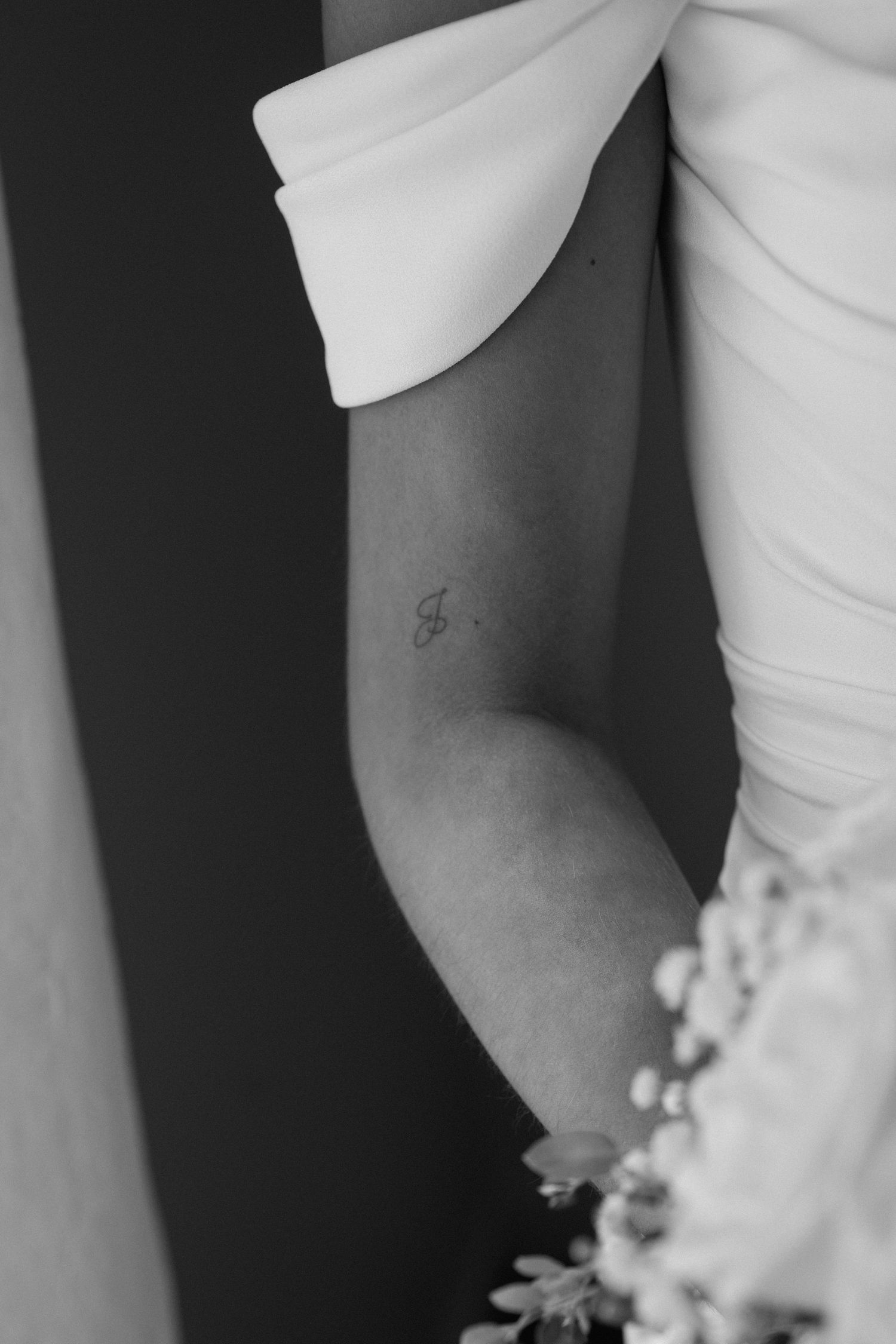 Close-up detail of a white wedding dress sleeve against a dark background.