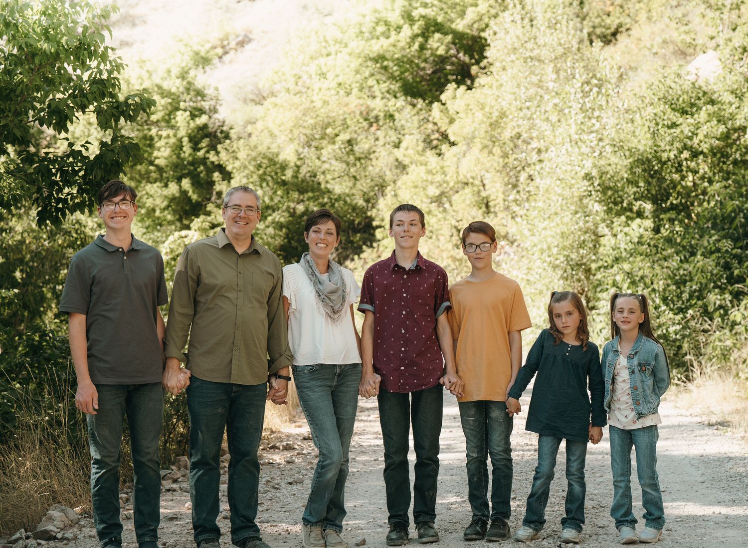 Family posing for photo in the middle of a dirt road.