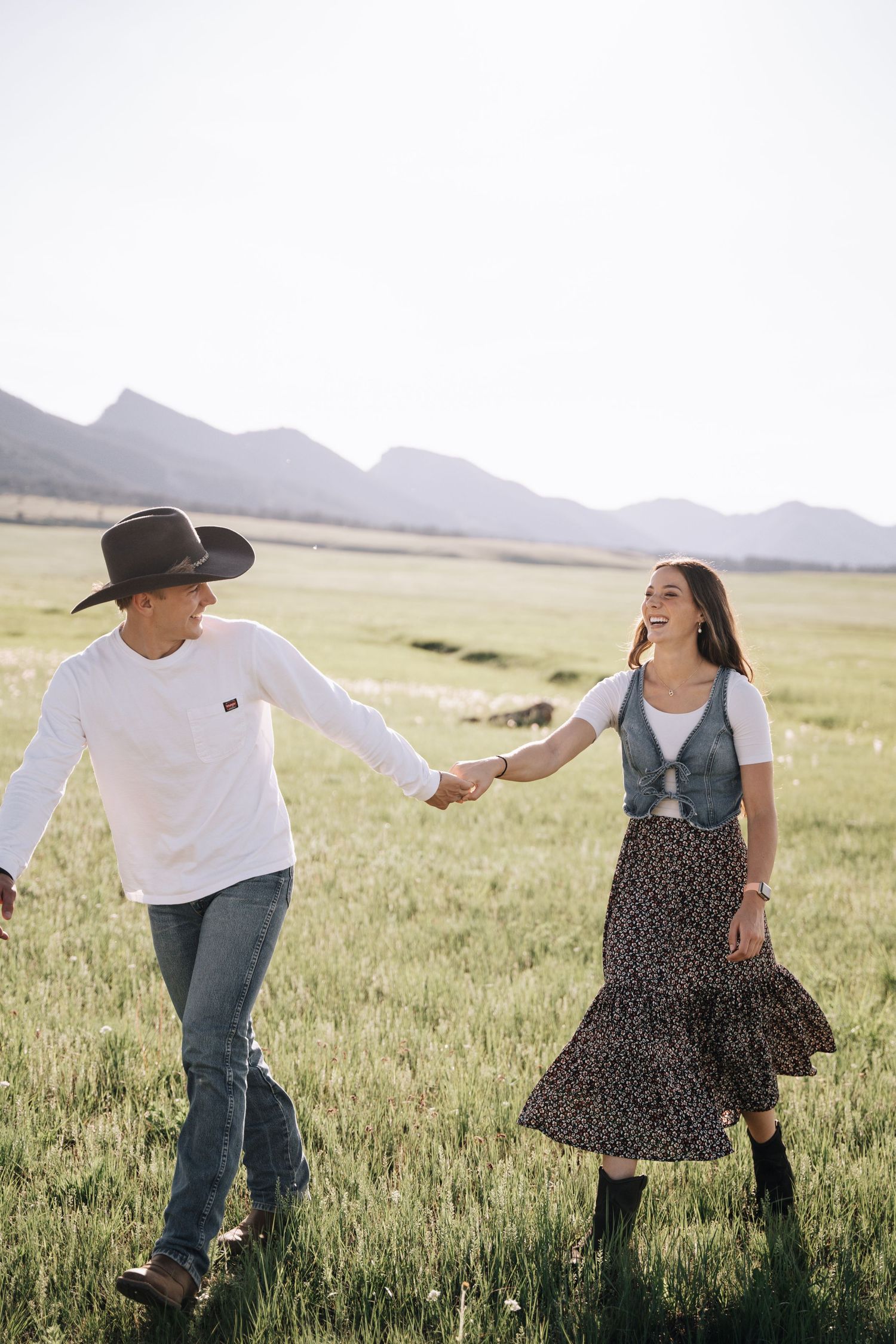 Girlfriend posing with boyfriend in field with sun in the back.