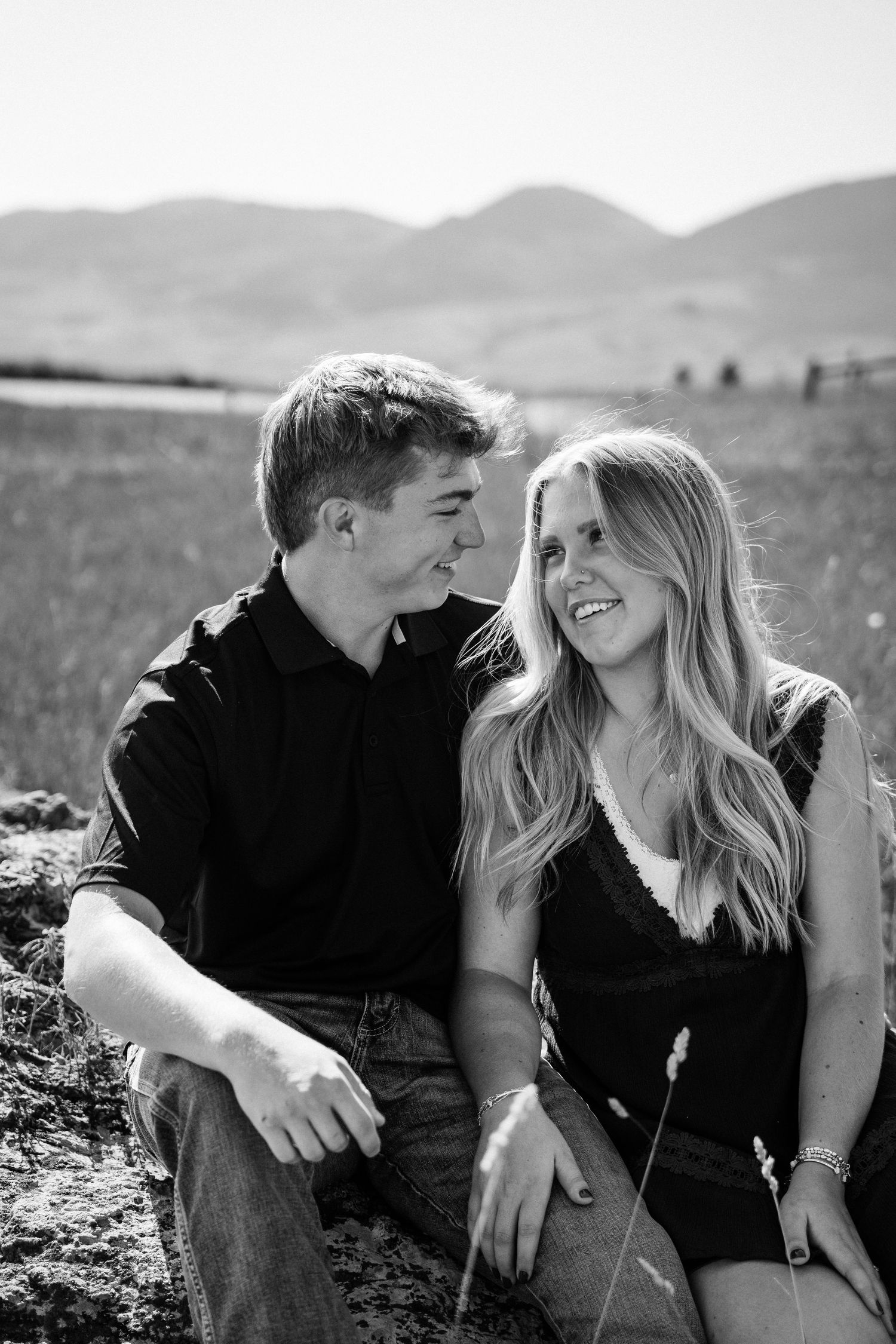Girlfriend posing with boyfriend in field with sun in the back.