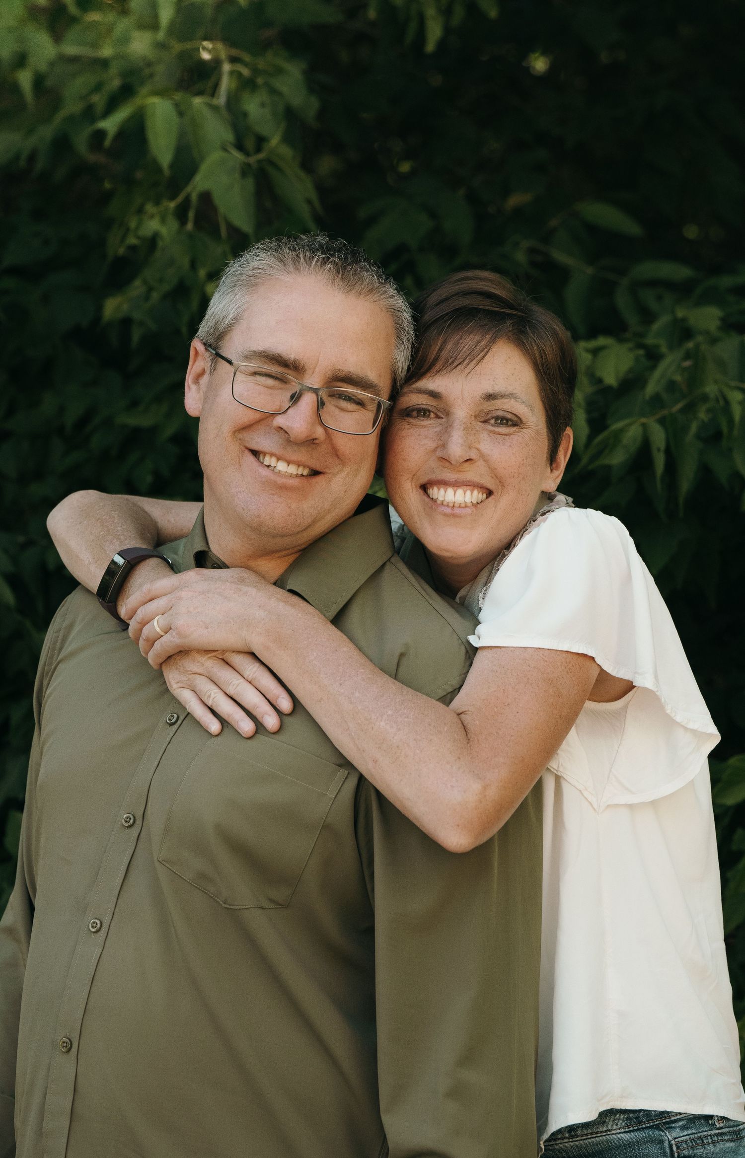 Couple posing in front of greenery