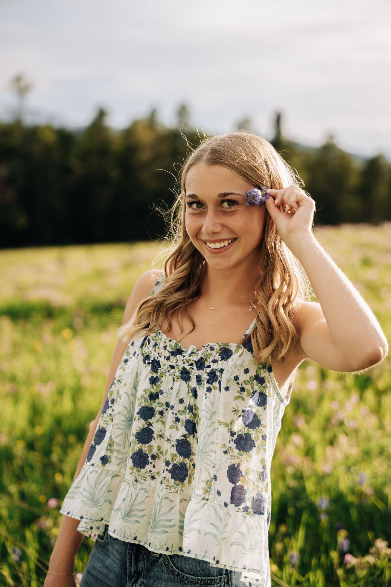 Girl looking into camera with her hand holding a flower behind her ear