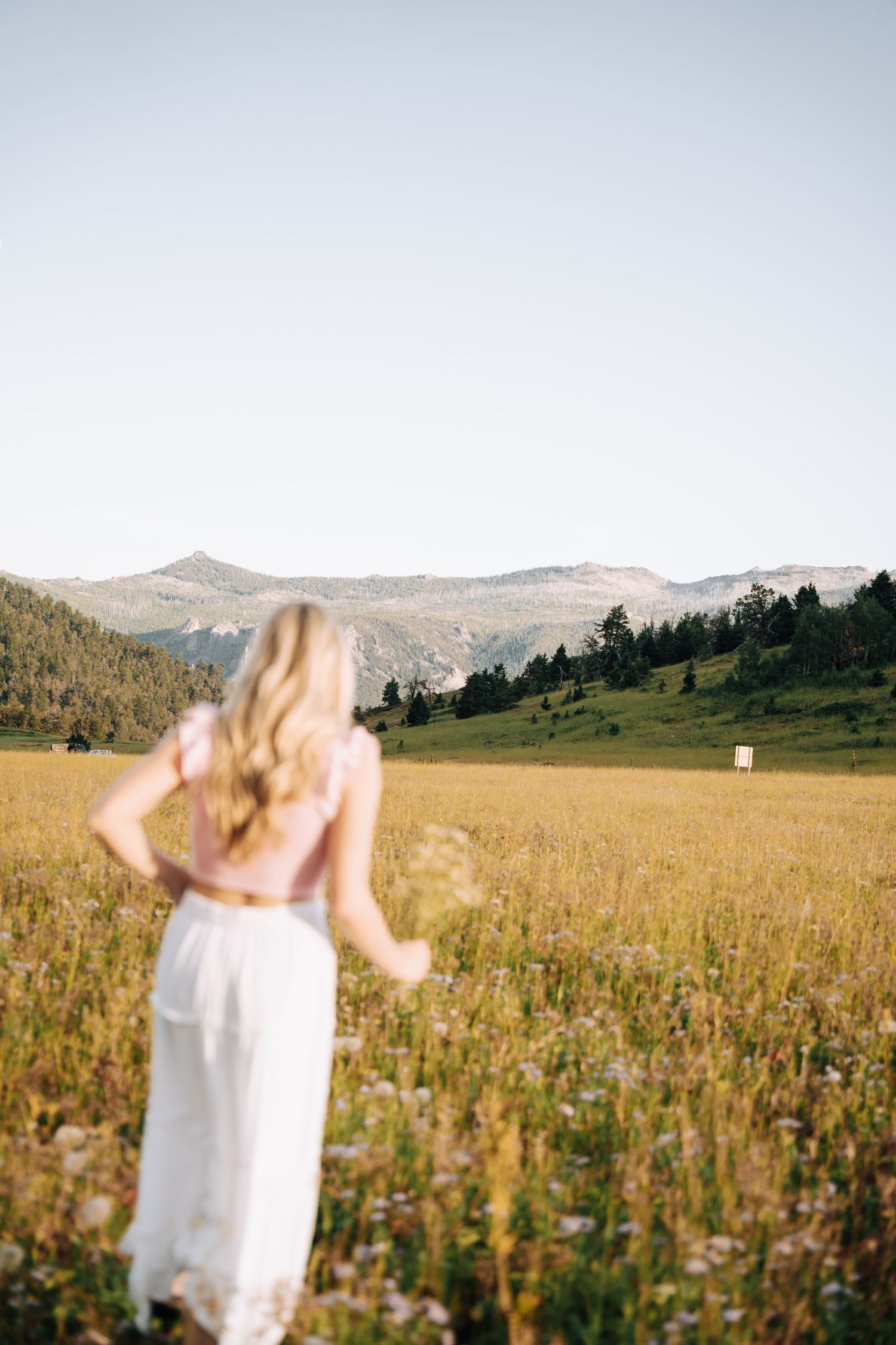 Girl looking over her shoulder at the camera with sun shining in the background.