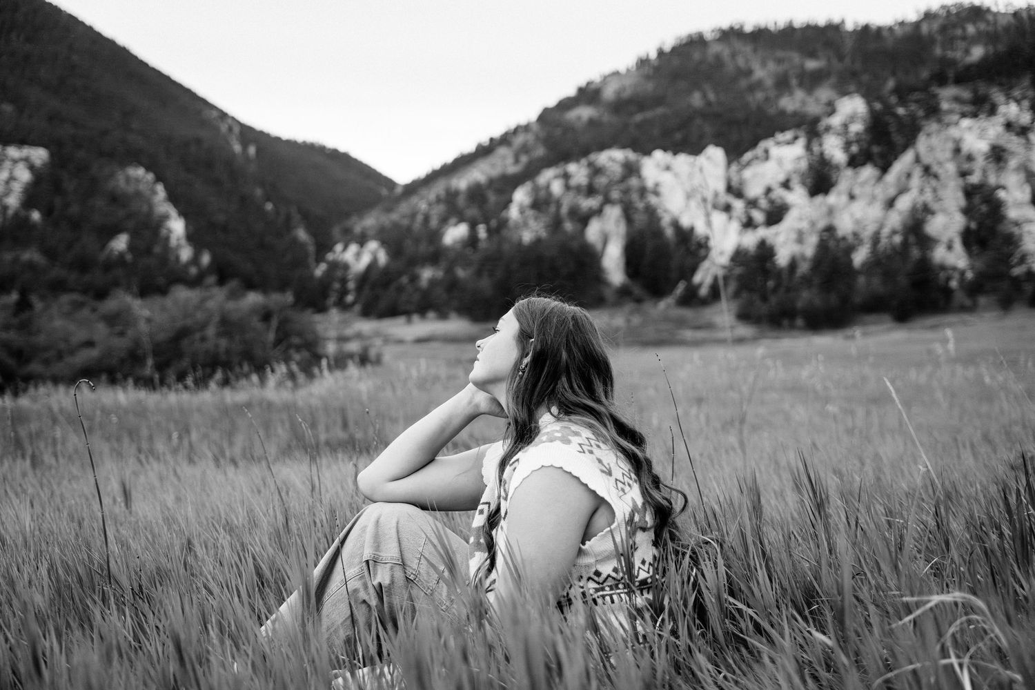 Girl sitting while looking at the mountains in the background.