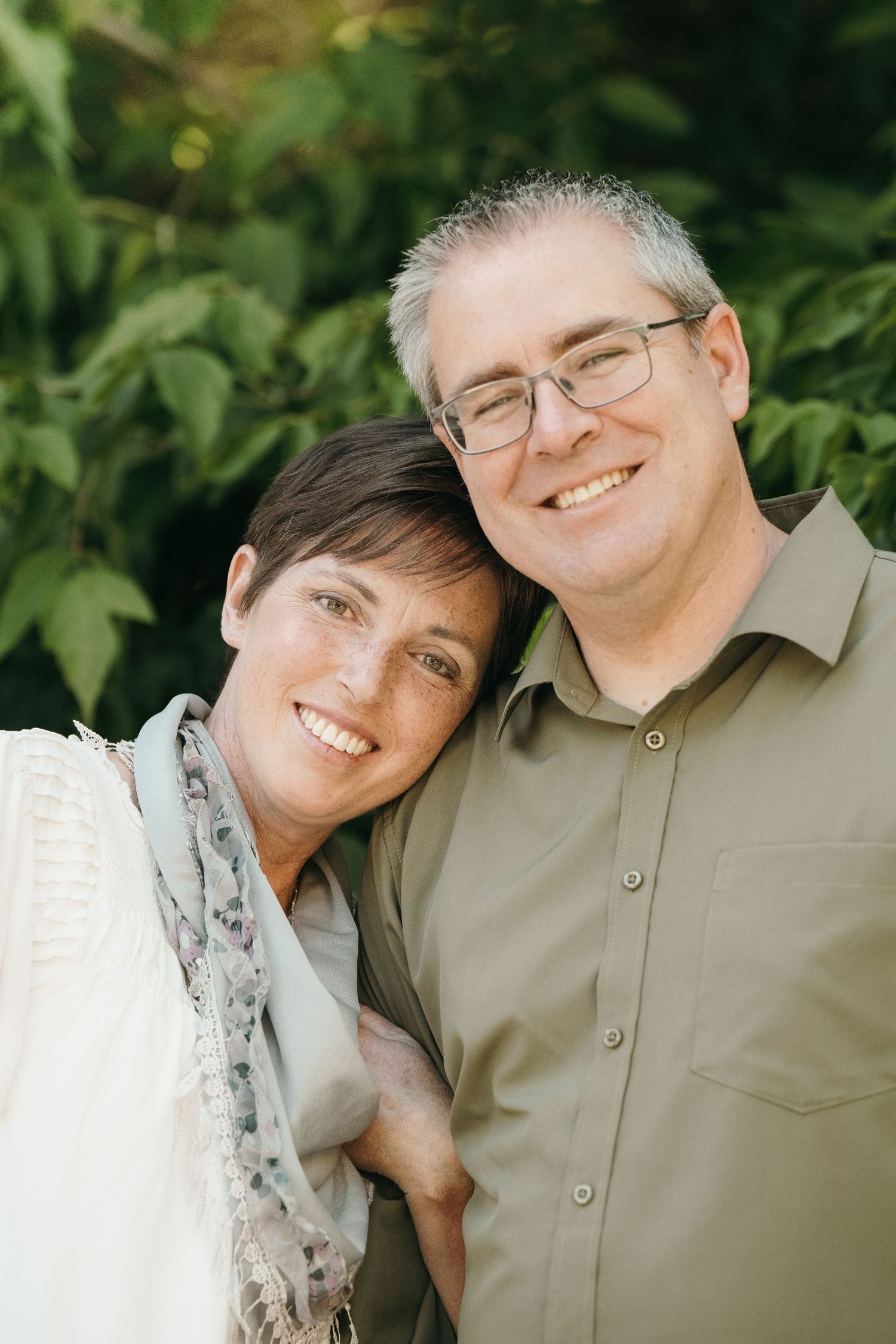 Couple posing in front of greenery