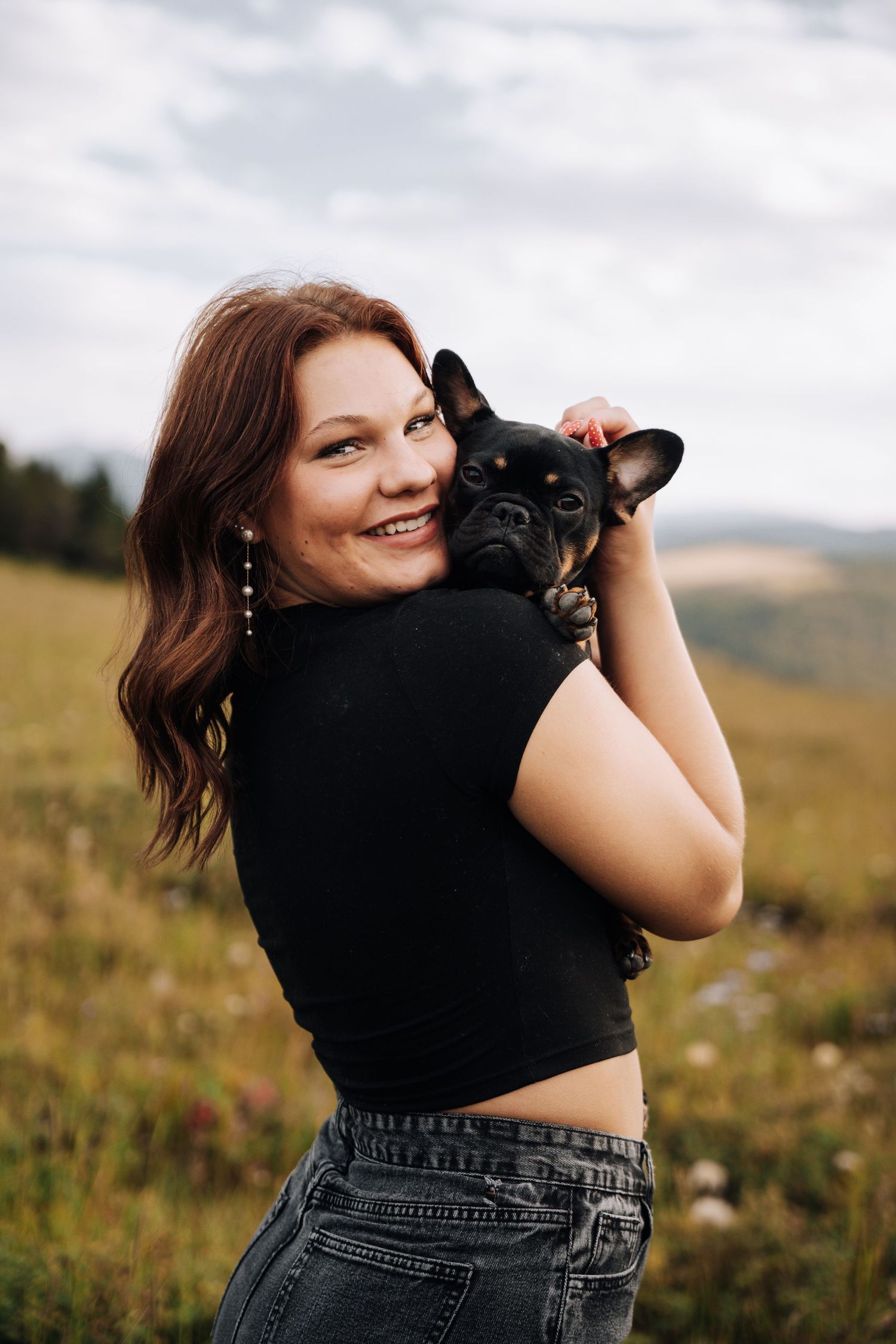 Girl Holding dog on her lap in a field of flowers