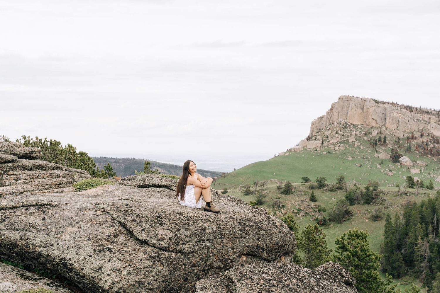 Girl sitting on a rock with a wide shot of the surrounding landscape