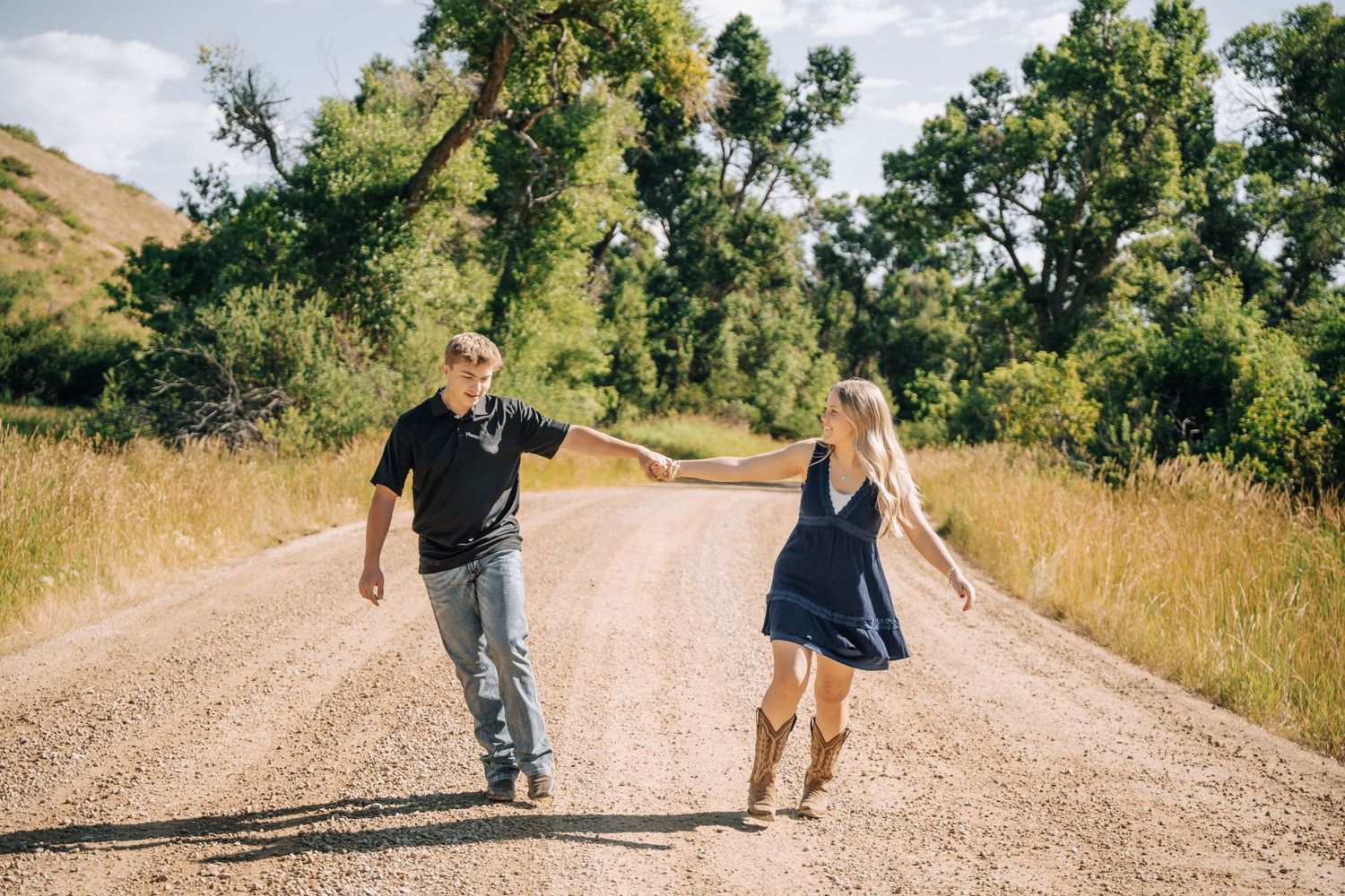 Girlfriend posing with boyfriend in field with sun in the back.