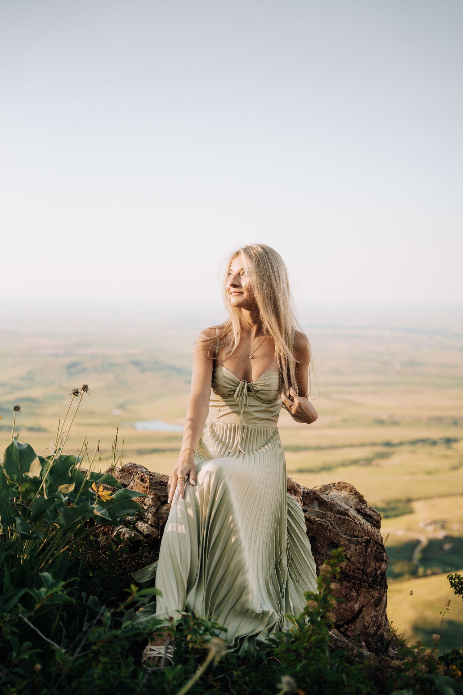 Girl in the middle of a yellow flower field. Mountains and open green spaces in the background.