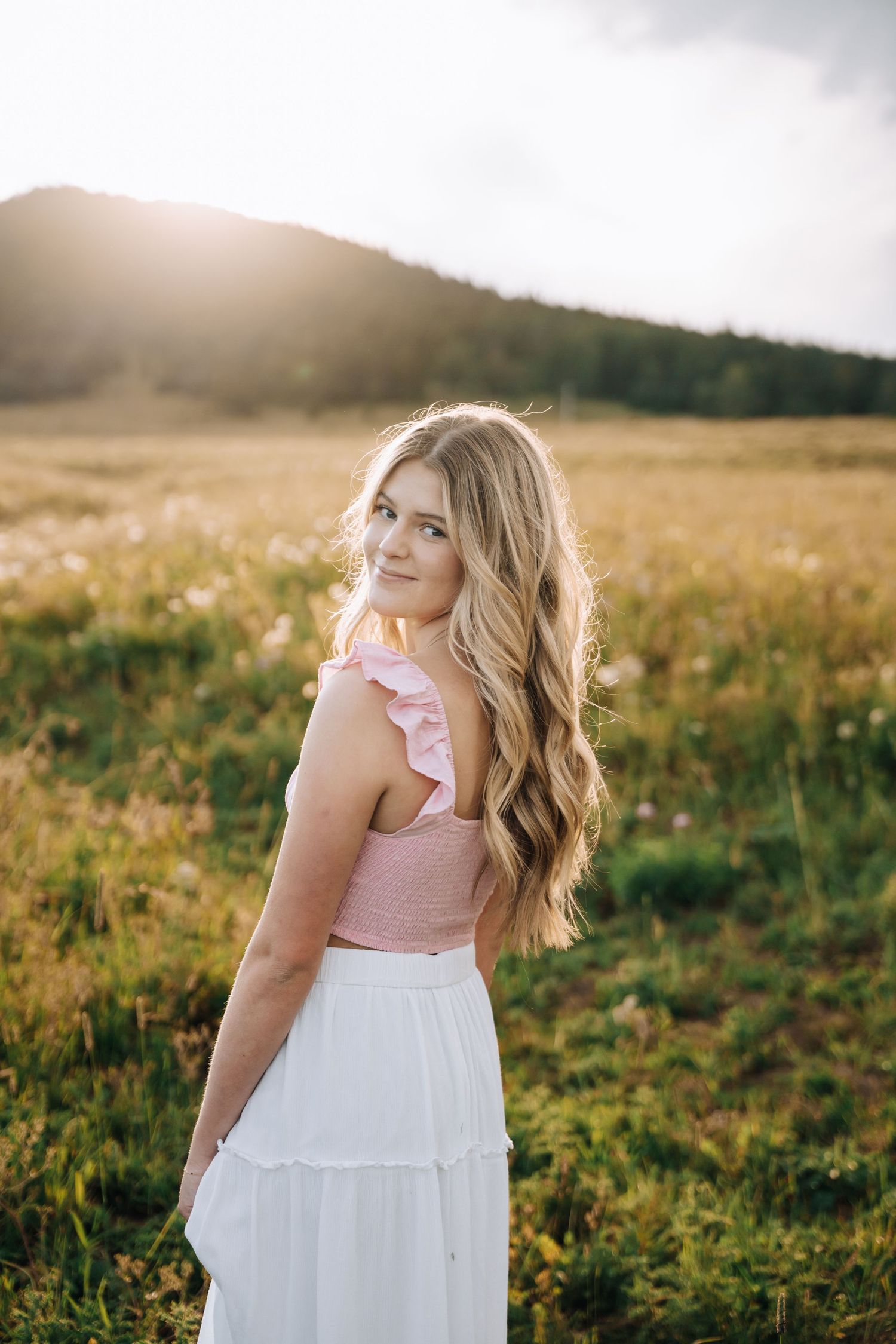 Girl looking over her shoulder at the camera with sun shining in the background.