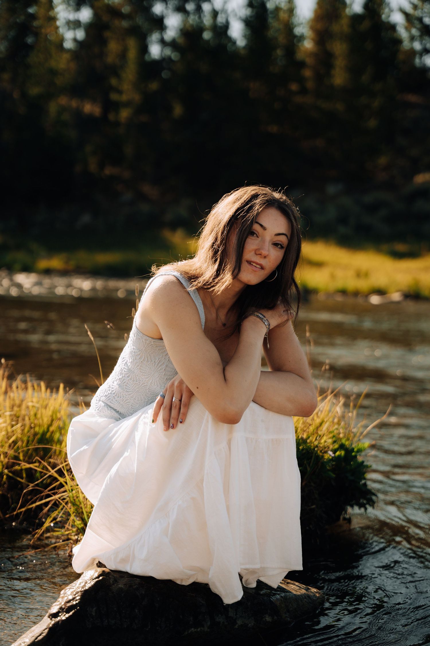 Womens senior session next to river while wearing flowy clothes