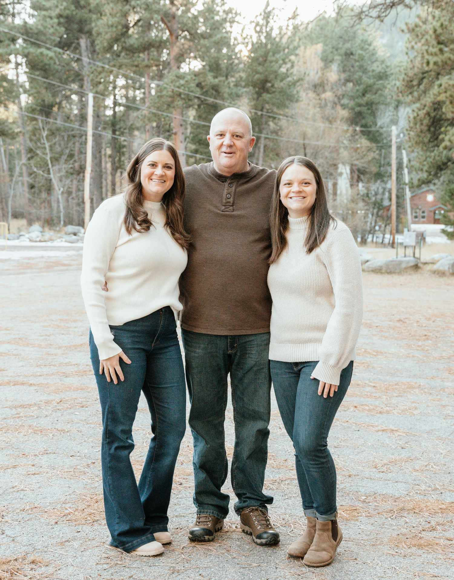 Dad standing and posing with his two of his adult daughters.