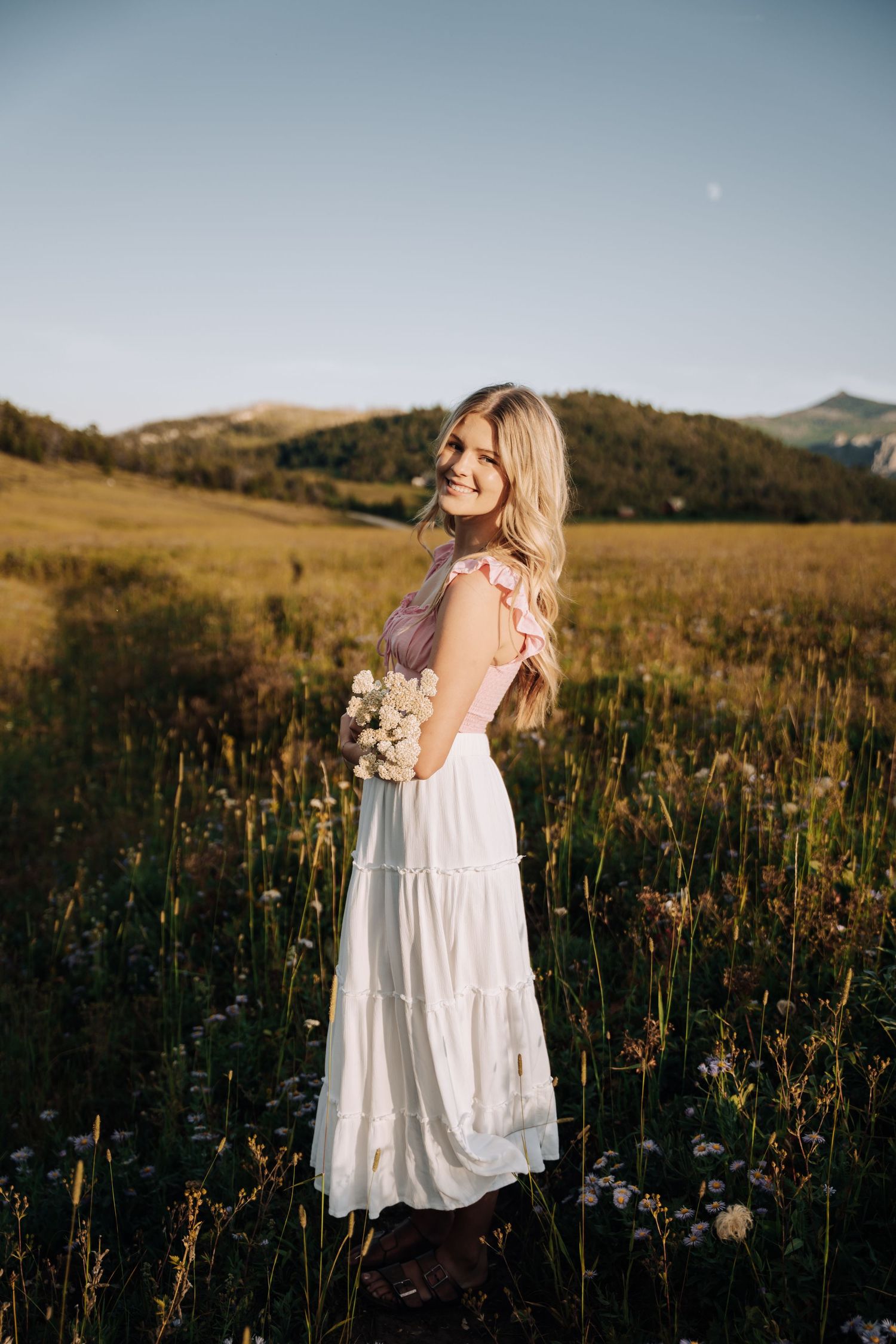 Girl looking over her shoulder at the camera with sun shining in the background.
