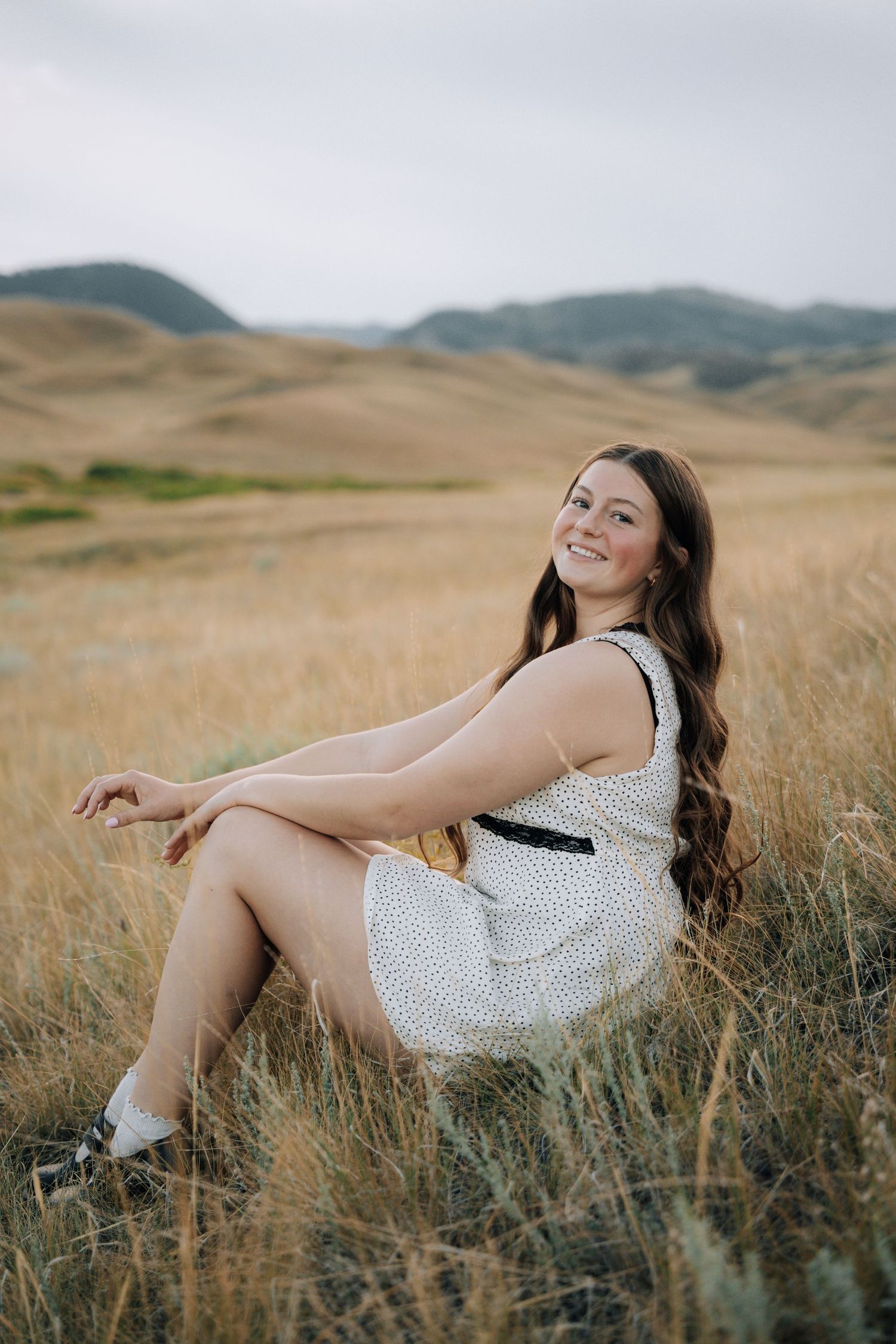Girl sitting while looking at the mountains in the background.