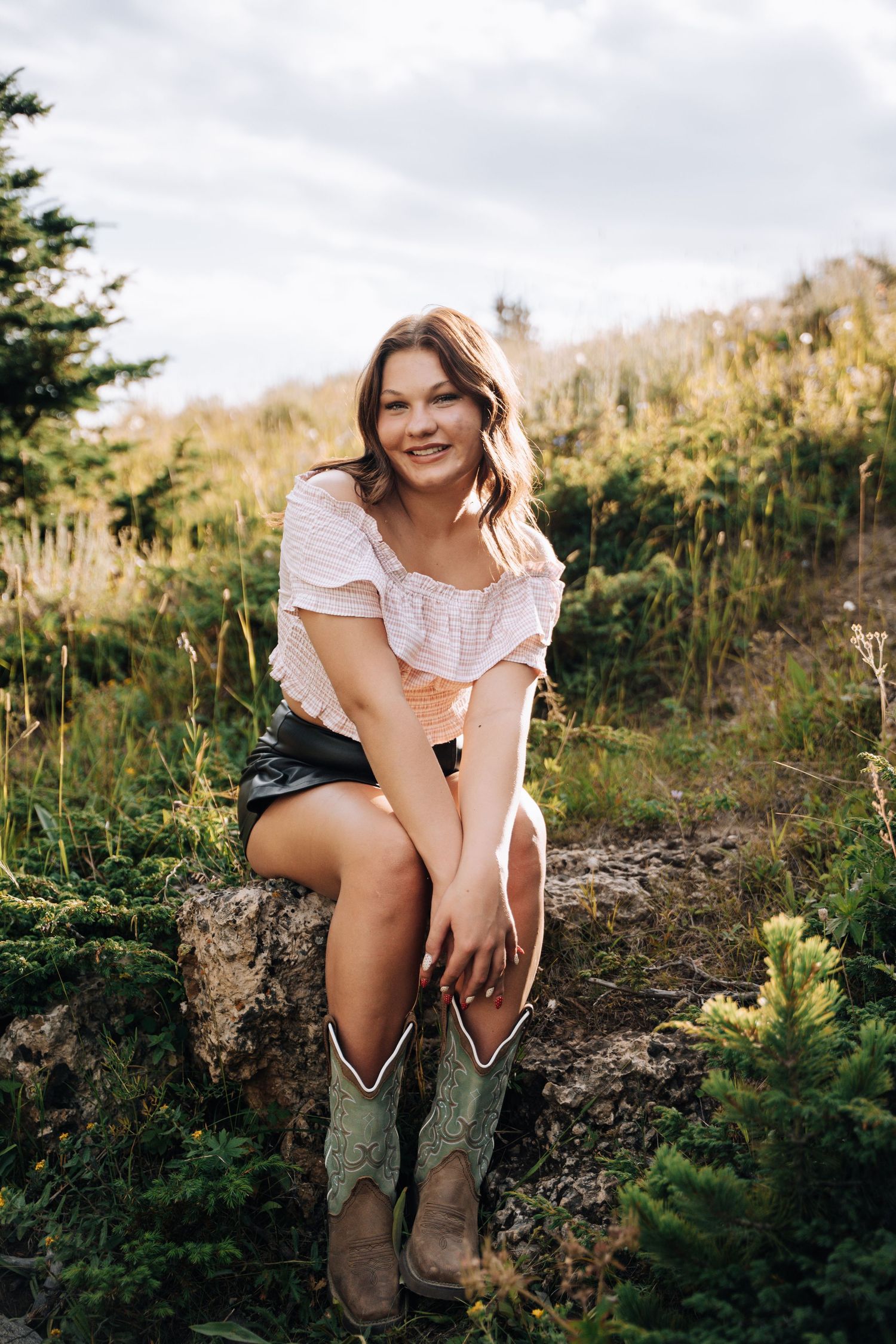 Girl sitting on a rock looking towards camera