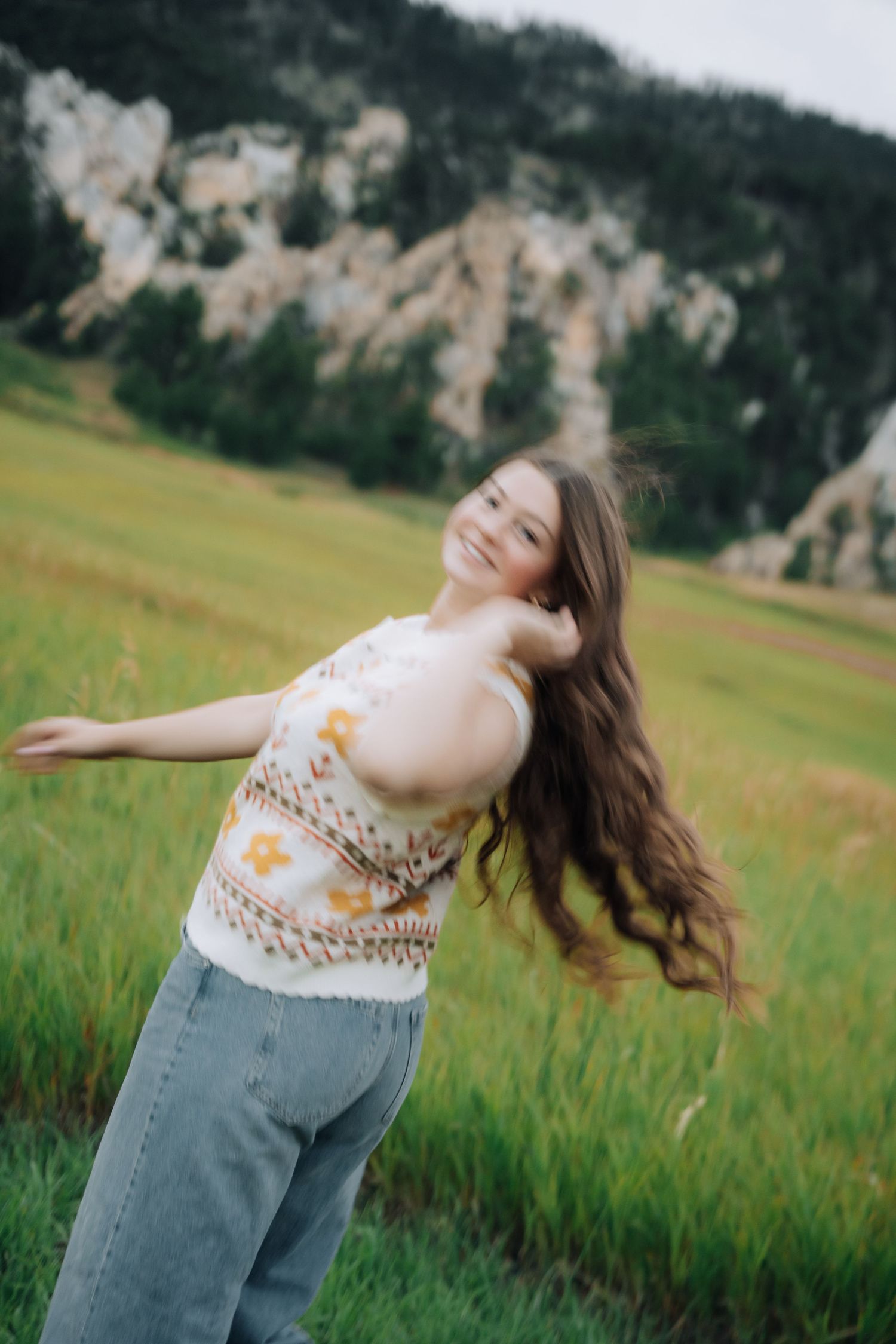 Blurry shot of a girl twirling, upwards angle with mountains in the background.