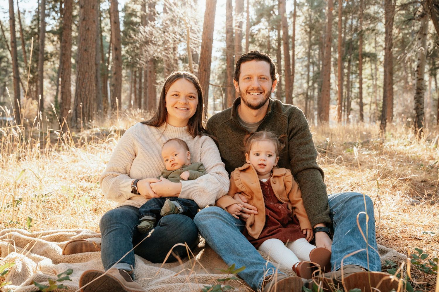 Family photo sitting on a blanket in the woods.