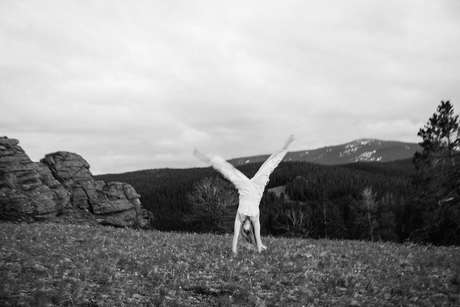 Girl doing a cartwheel wearing overalls.
