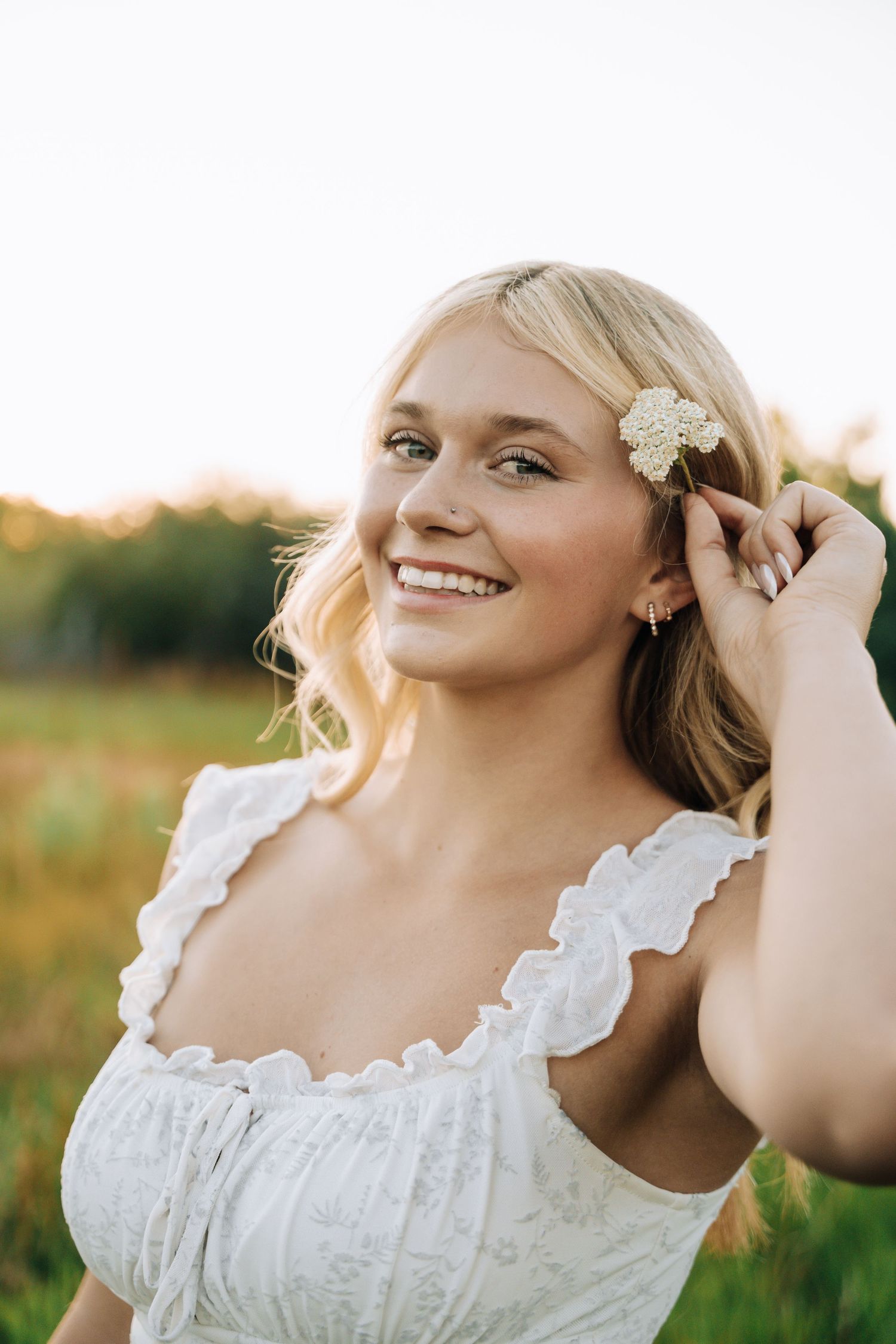 Girl looking at camera while putting flower behind her ear.