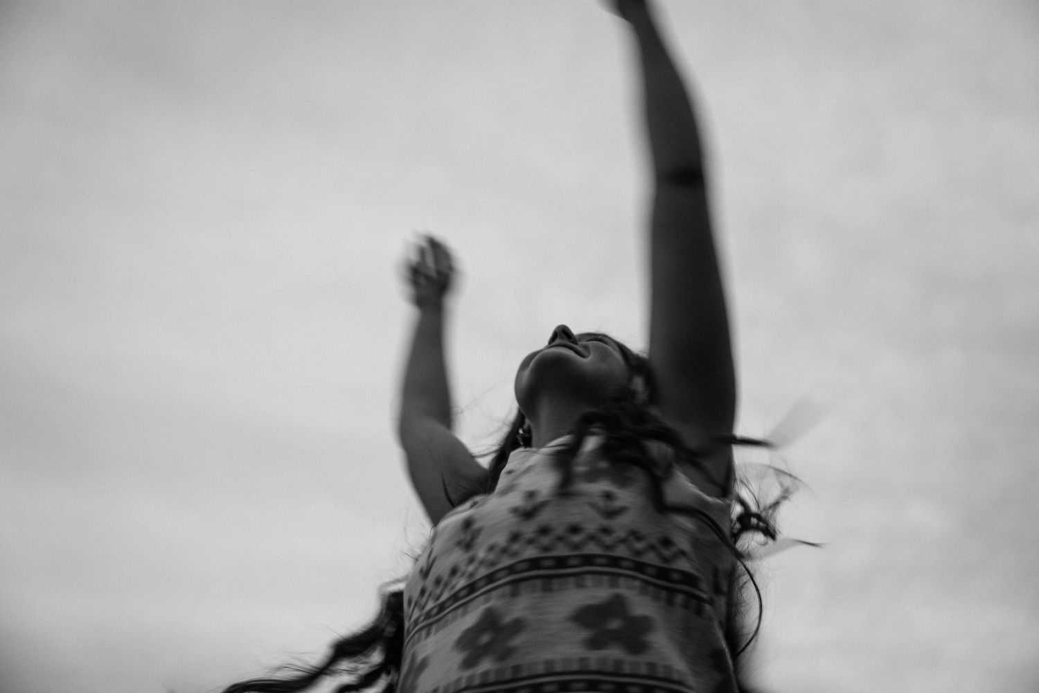 Blurry shot of a girl twirling, upwards angle with sky in the background.