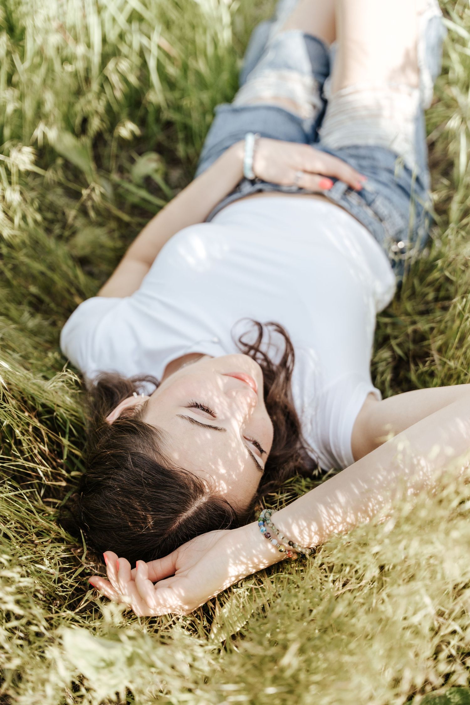 Girl laying in the grass, camera angle is directly above her.