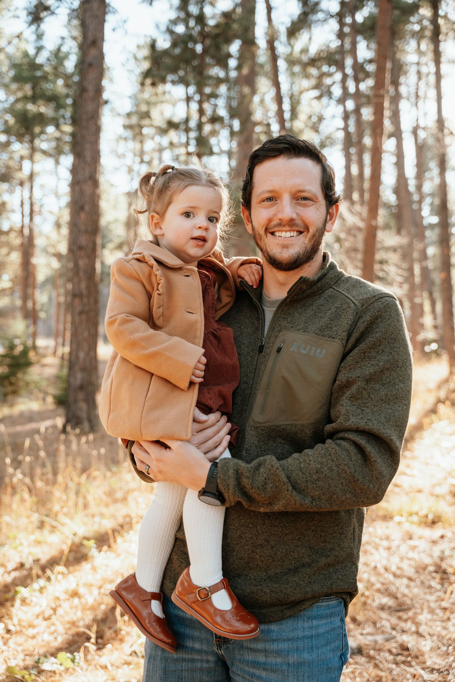 Dad holding daughter looking at camera