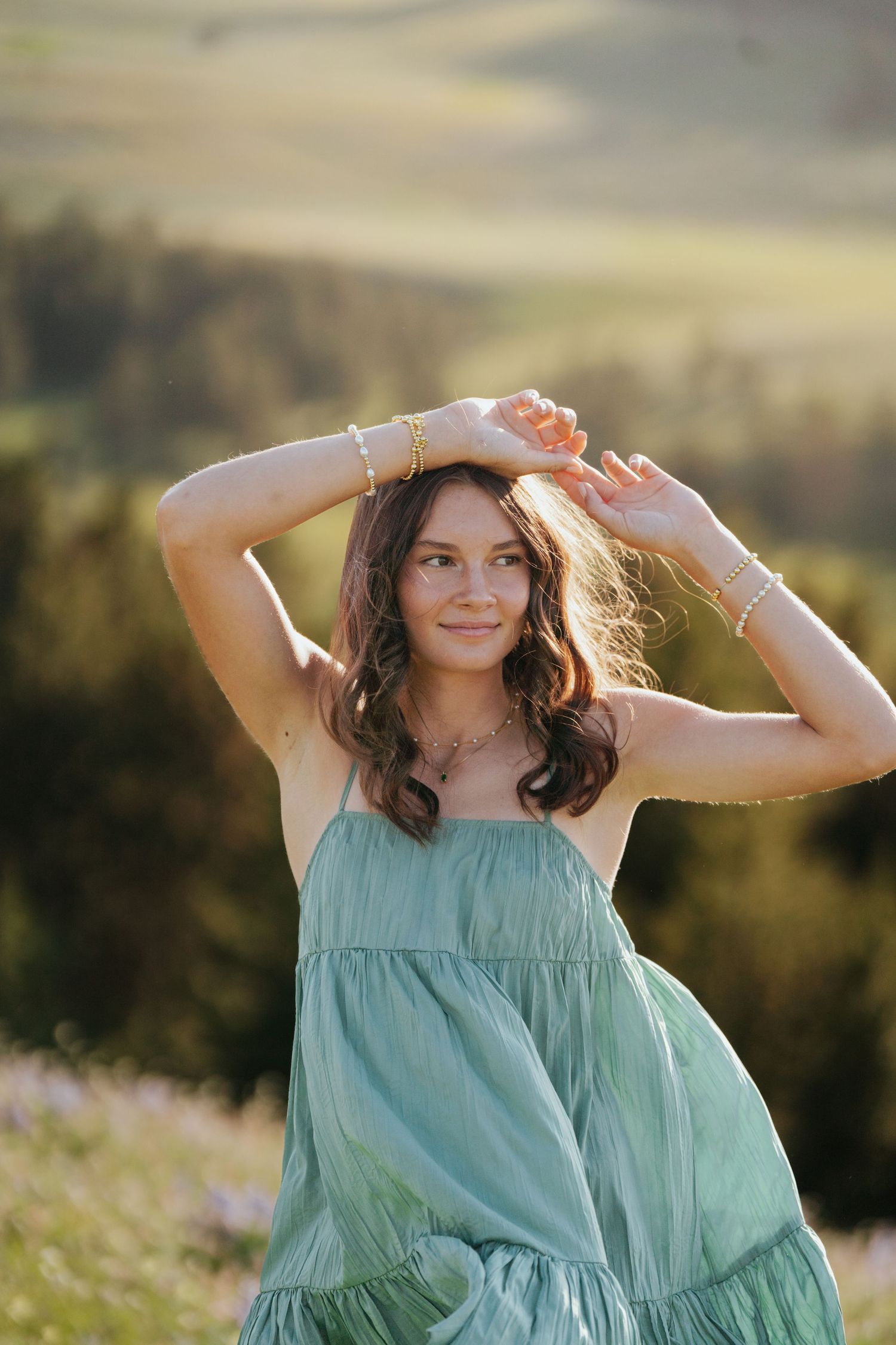 Girl holding her hands above her head while posing in a flower field.