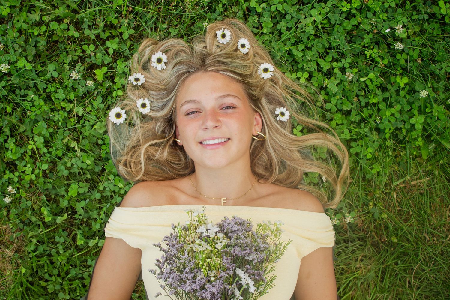 Person relaxing in green field with white daisies and natural lighting.
