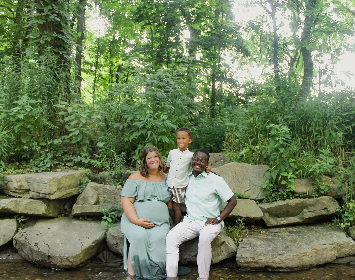 Couple sitting together on natural stone rocks in a wooded forest setting.