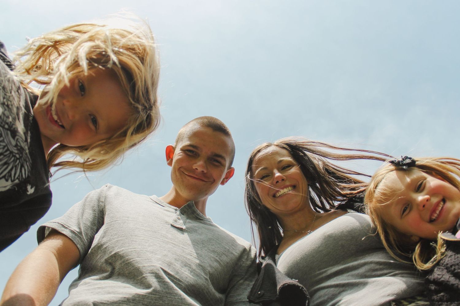 Friends posing together against blue sky background during outdoor photoshoot.