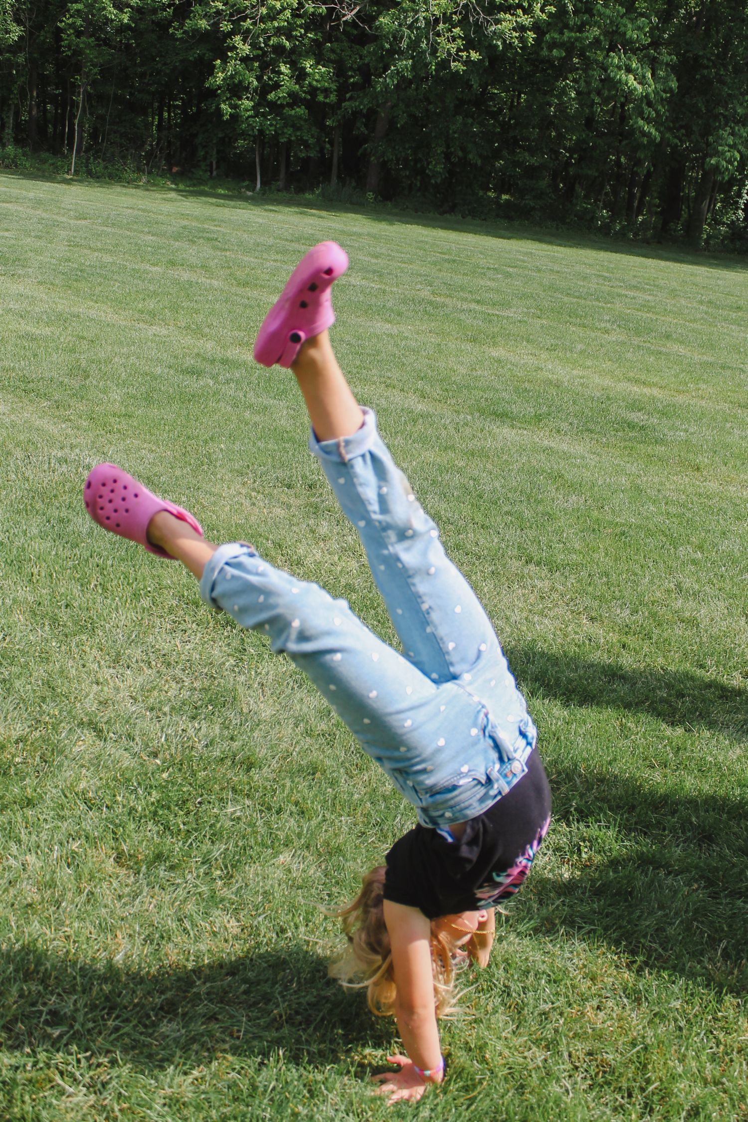 A series of photos showing someone doing cartwheels on a grassy hillside while wearing jeans and pink shoes.