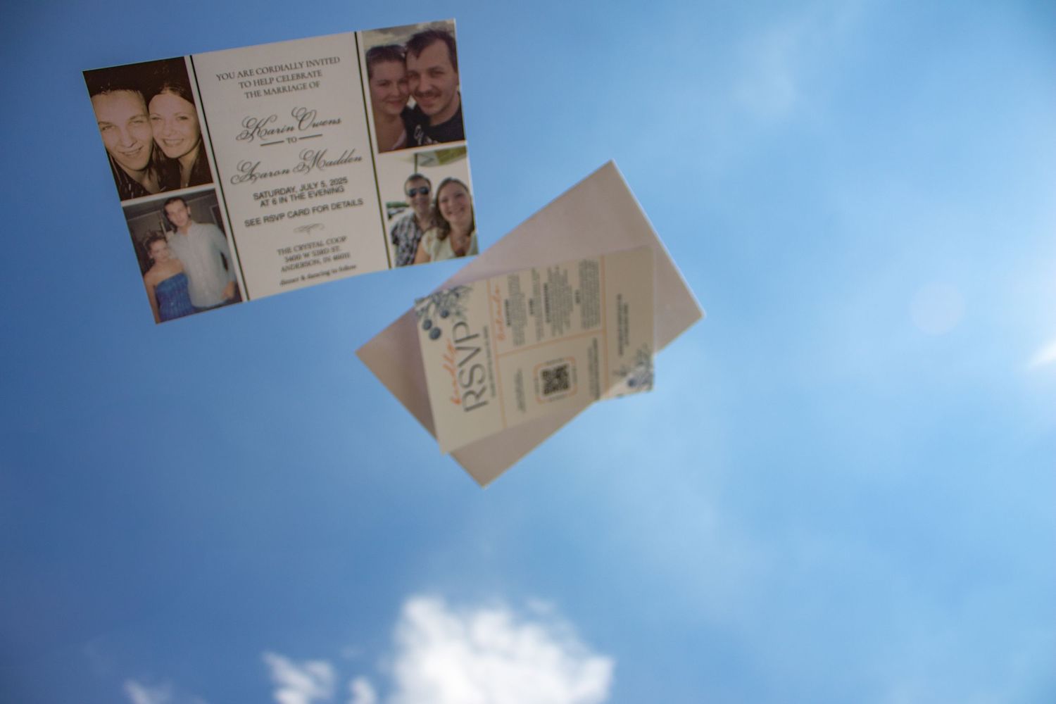 Wedding invitation and cards photographed against bright blue sky with clouds.