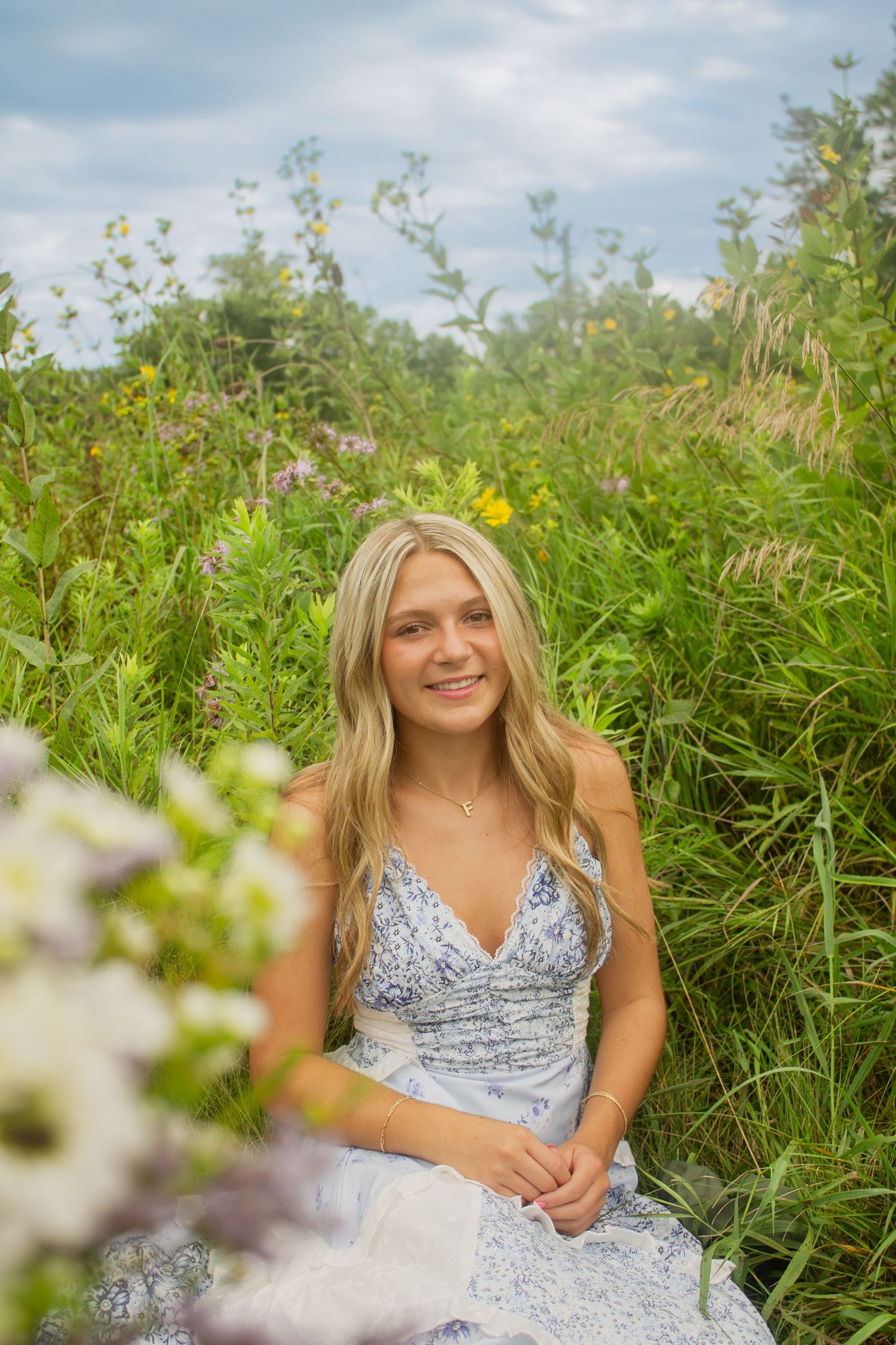 Summer portrait session in a field of tall grass and wildflowers on a bright day.