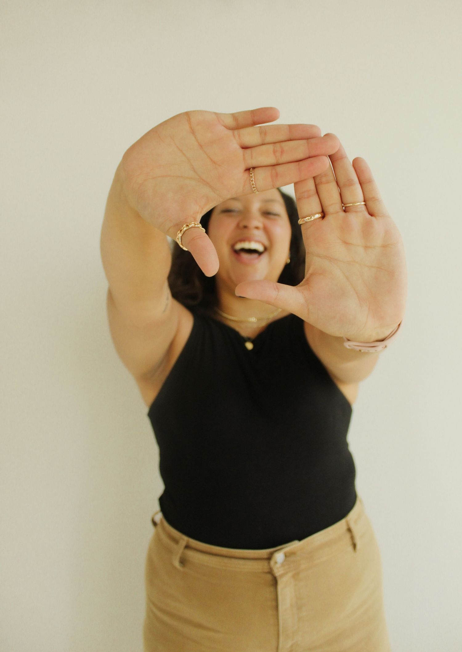 Series of close-up shots showing hands crossing in front of torso wearing black top and beige pants.