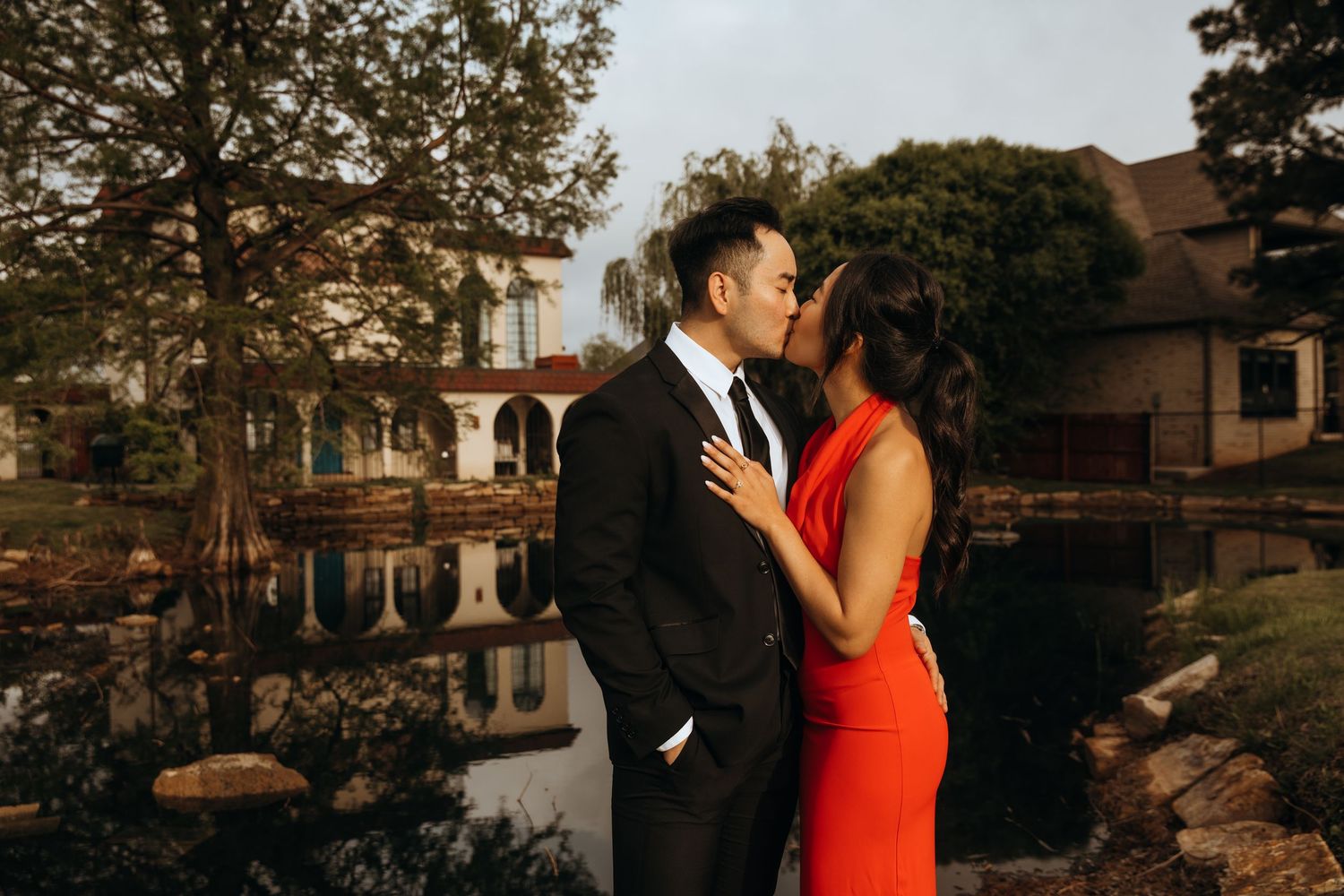 A couple celebrates their engagement in formal attire outdoors during golden hour.