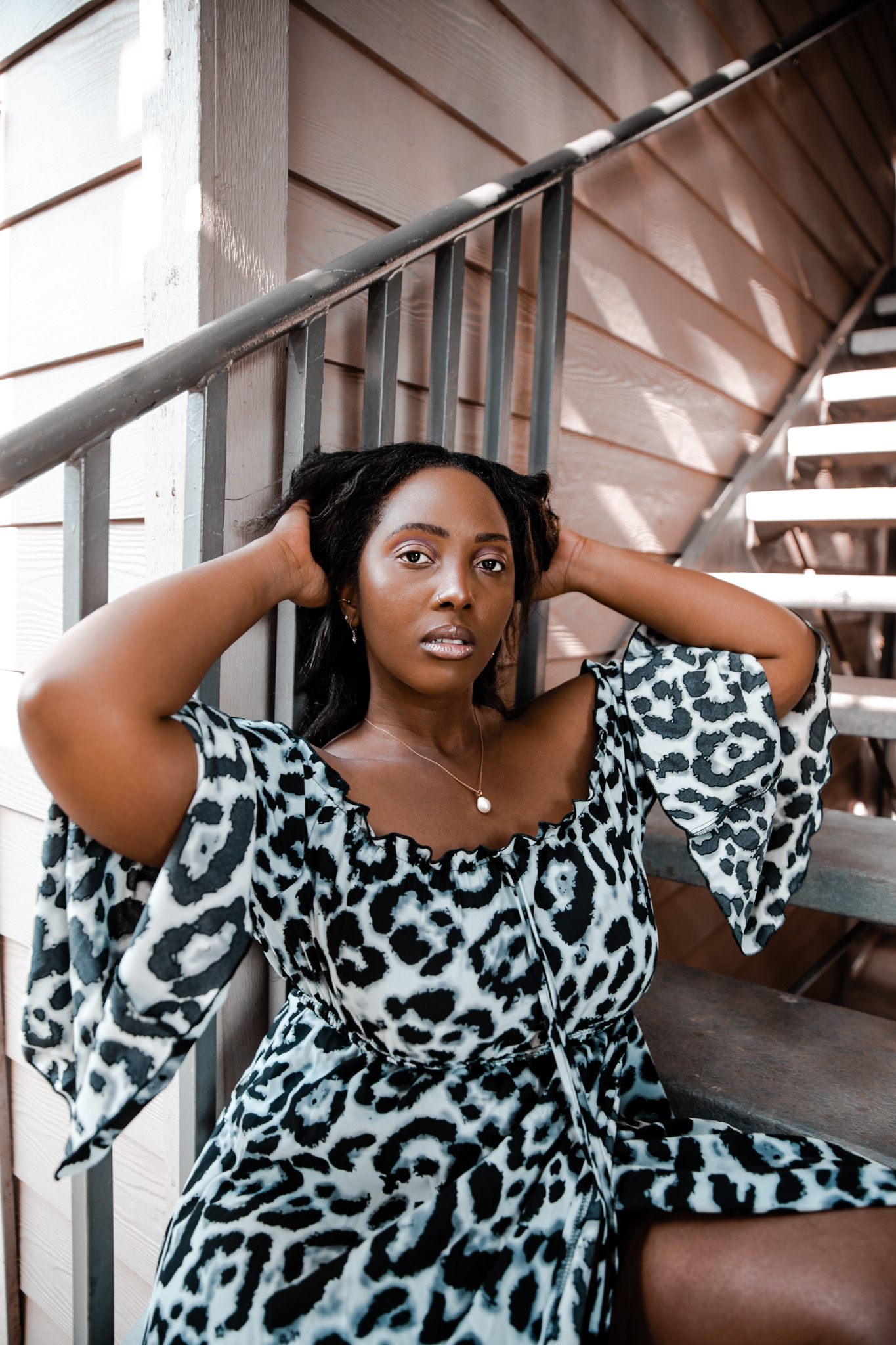 Fashion portrait in black and white animal print dress against industrial background.