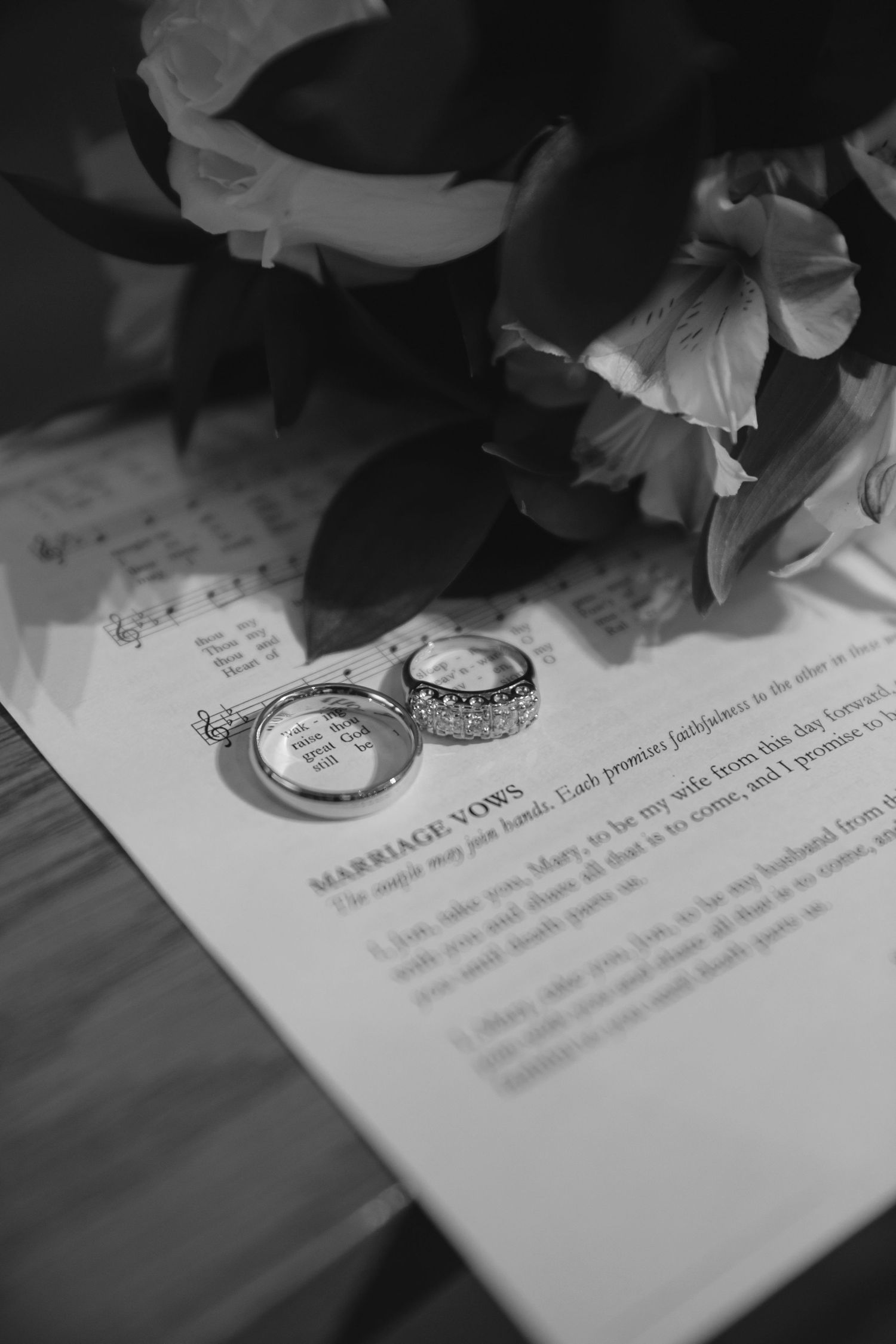 Wedding ceremony details showing document signatures and floral decorations in black and white.
