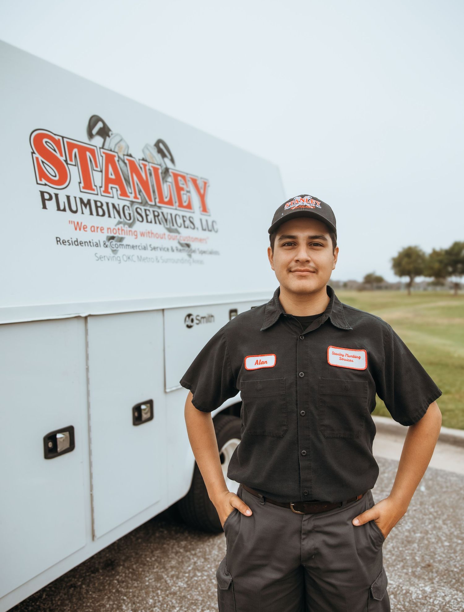 Plumbing service workers in uniform posing next to company vehicle outdoors.