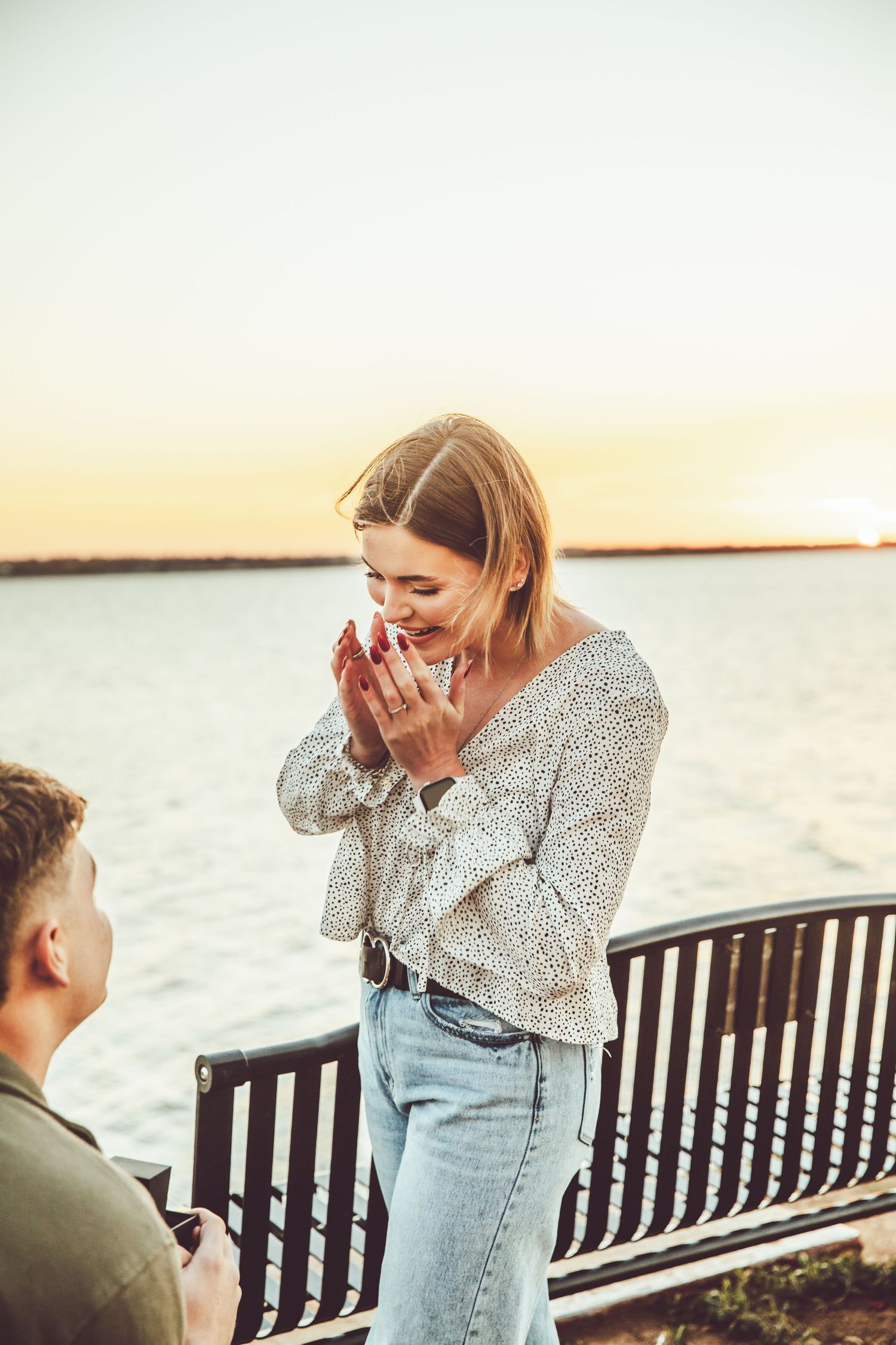 A couple shares an emotional moment at sunset by the water.