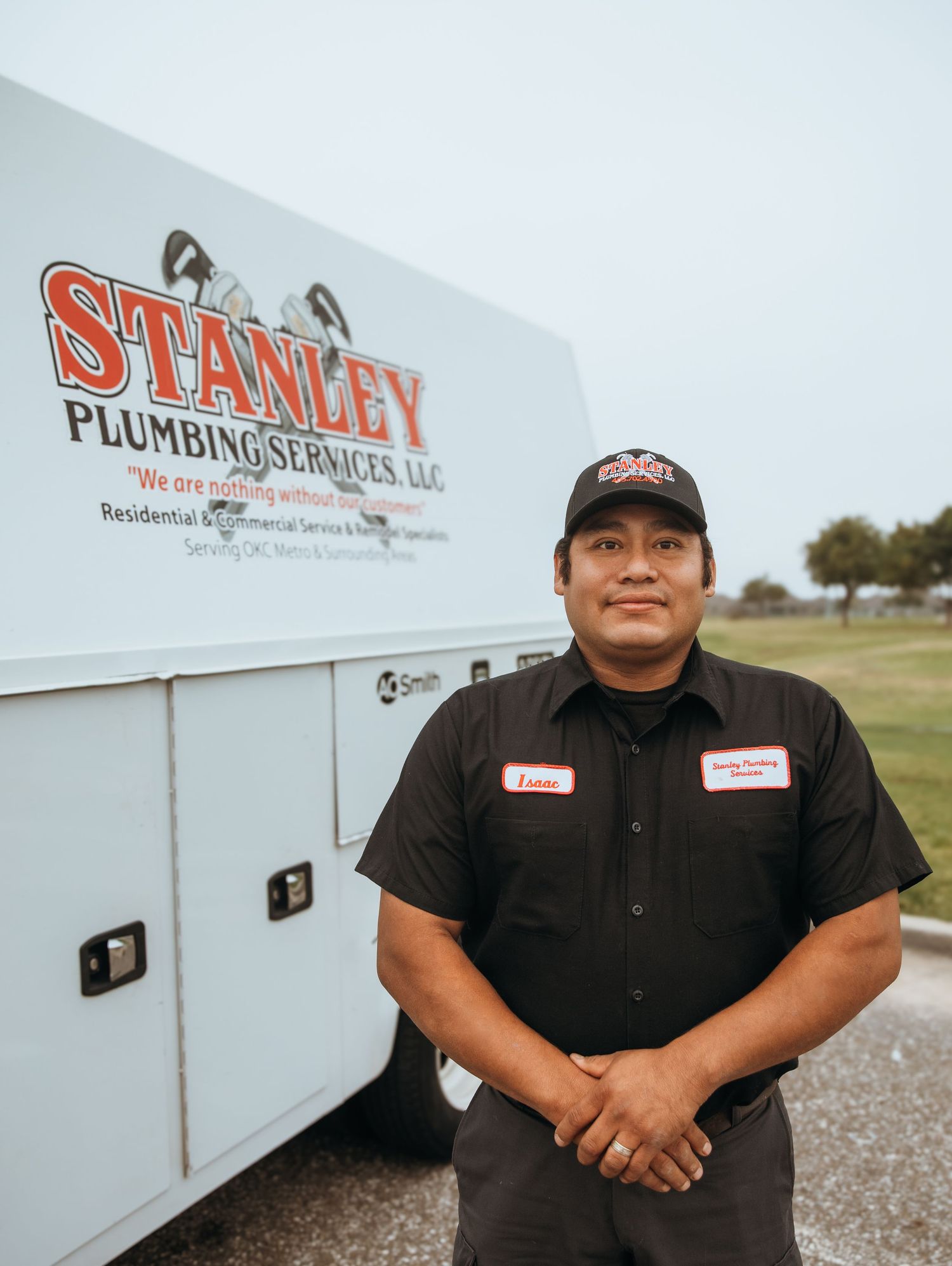 Professional plumbing service truck and employee standing in front of Stanley Plumbing Services.