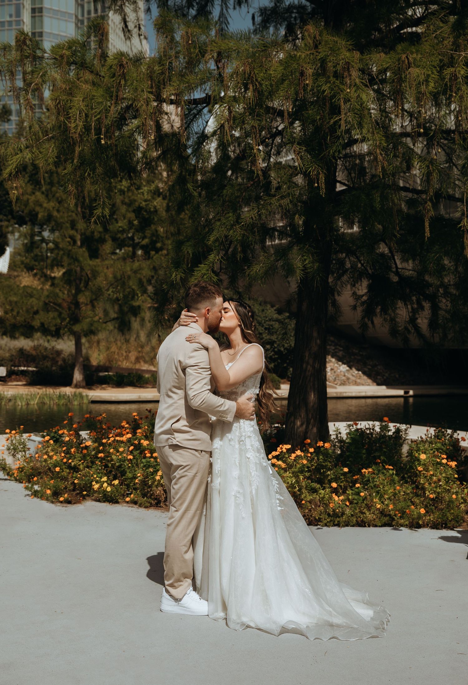 Wedding couple sharing intimate moments in a garden with yellow flowers and trees.