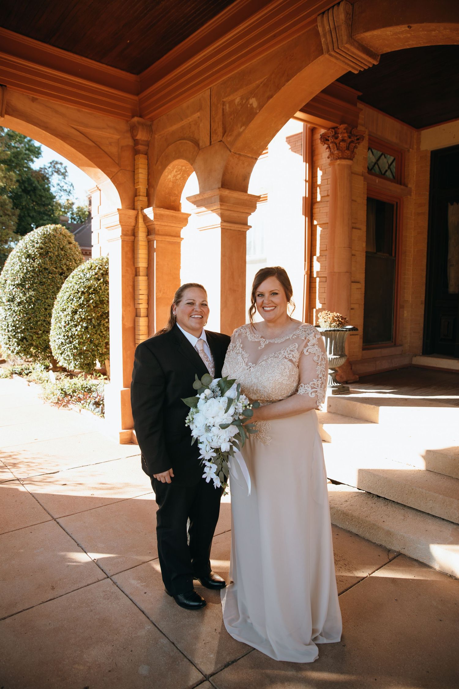 Wedding couple poses under ornate stone archways with natural lighting.